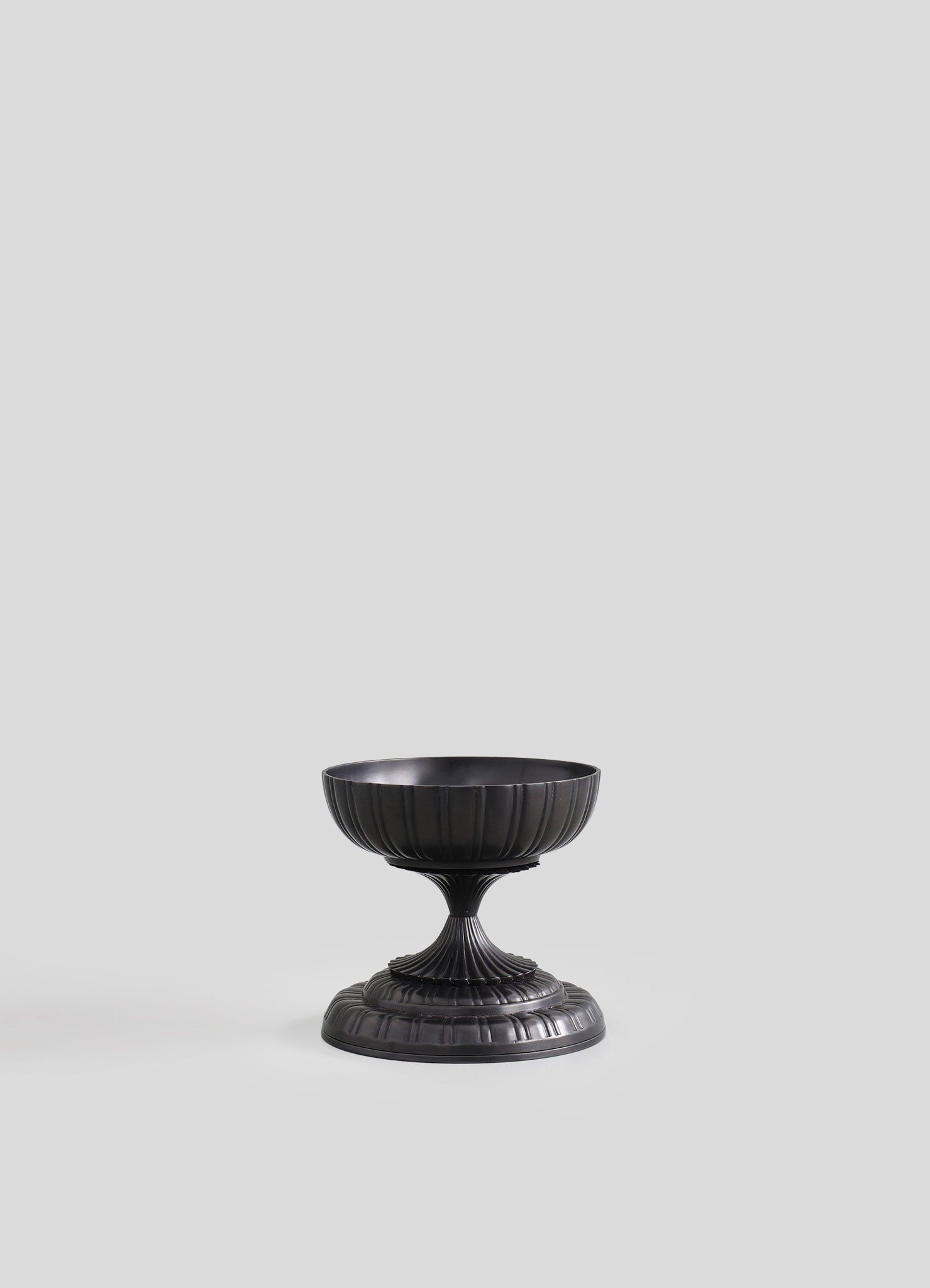 Black metal pedestal bowl with a ribbed, fluted design and a circular base, featuring a matte finish.