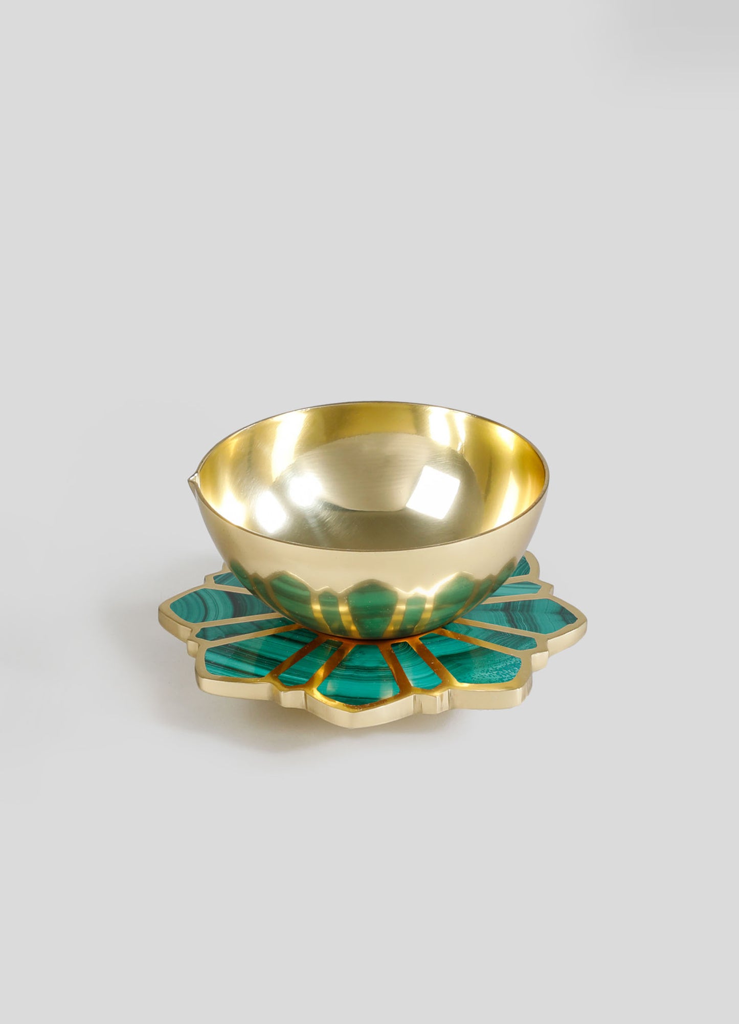A decorative brass bowl with a polished gold finish, resting on a teal and gold resin inlay base with petal-shaped design, suitable for serving or display.