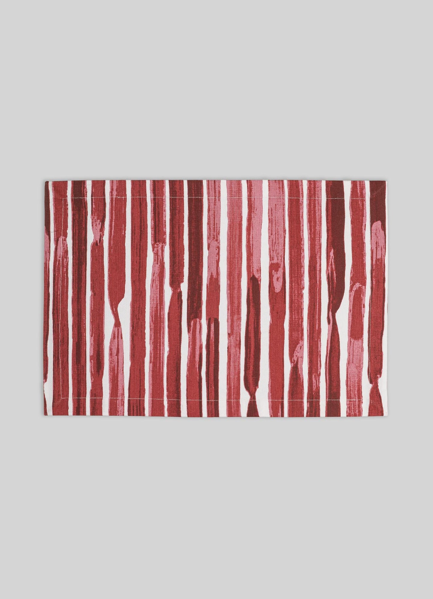 A rectangular textile rug with vertical red and pink brushstroke stripes on a white background. The rug has a contemporary style with bold, irregular patterns and a casual, artistic feel.