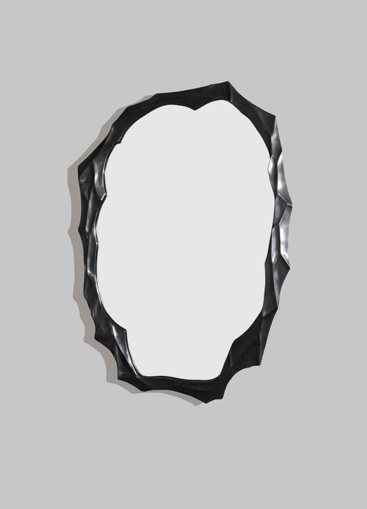 A decorative wall mirror with a textured, irregular black frame and an oval reflective surface.