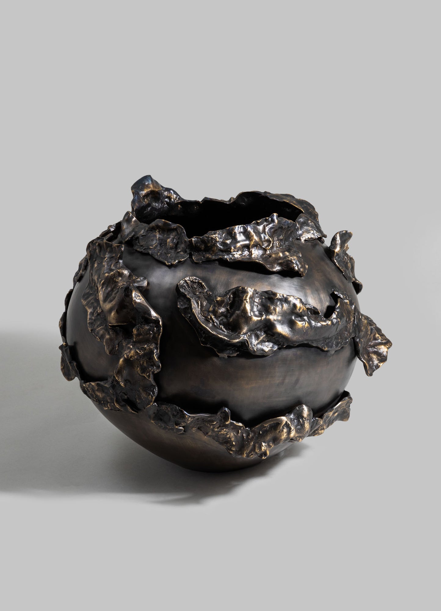 A black decorative ceramic bowl with an irregular, textured metallic bronze finish applied around the rim and surface, creating a sculptural, abstract pattern.