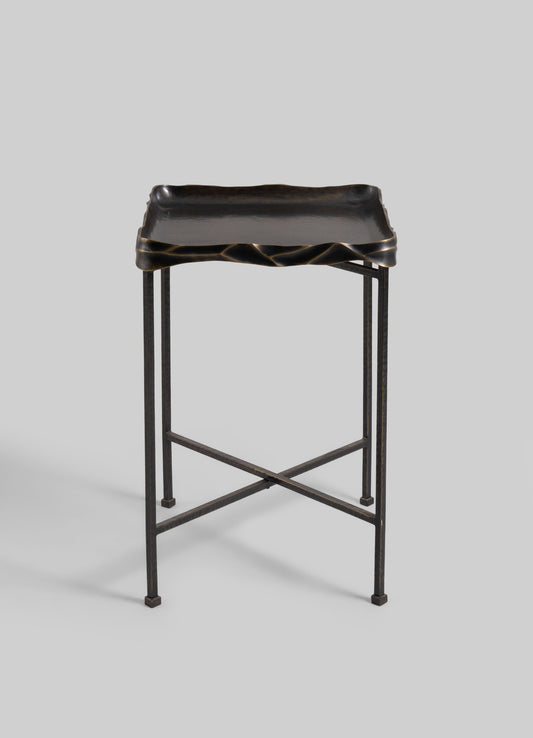 A black lacquered wooden tray with irregular, wavy edges and a smooth finish, mounted on a metal stand with slender, straight legs and crossbars.