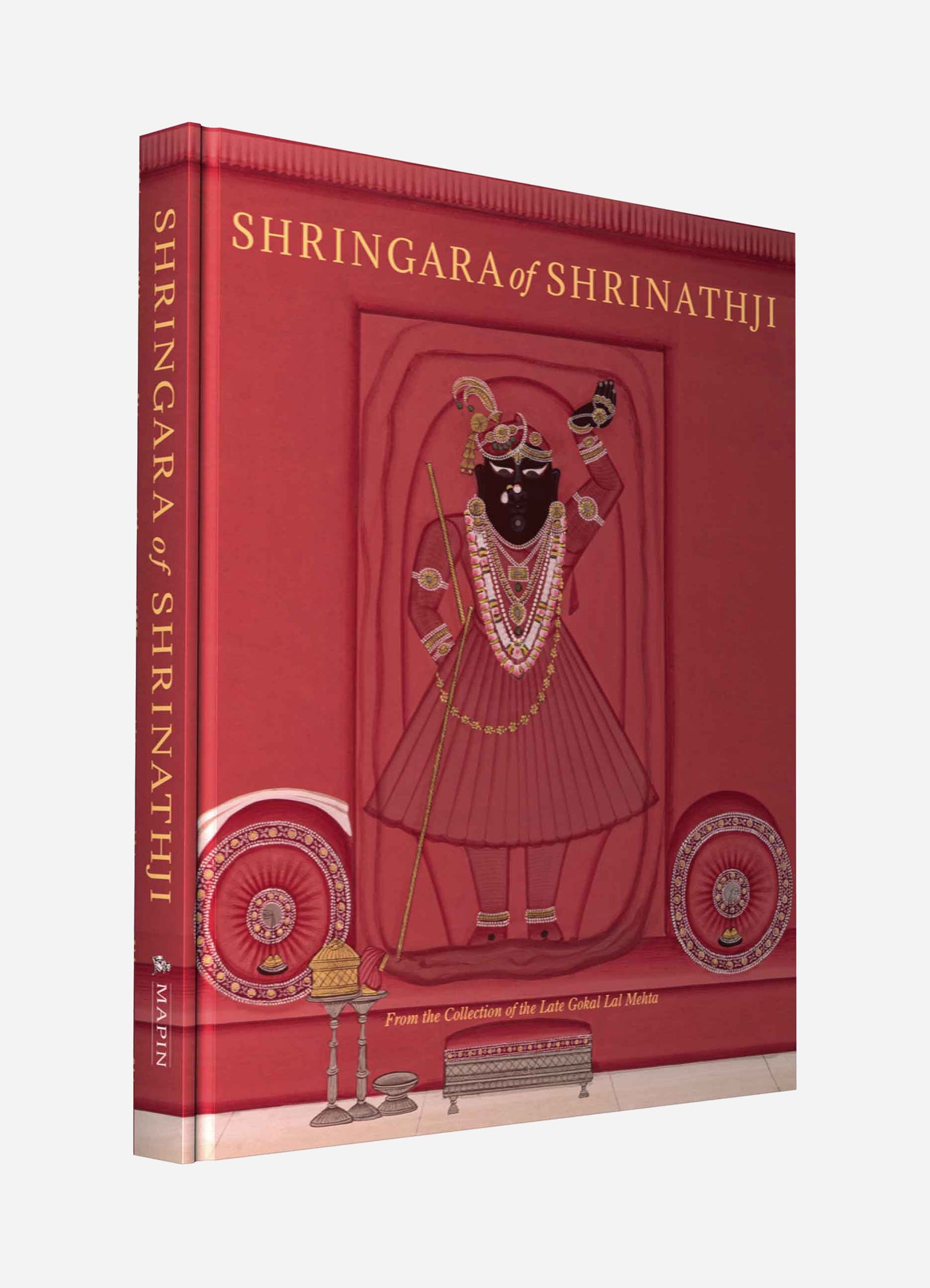 A hardcover book with a red cover featuring an illustrated icon of a Hindu deity in traditional attire, adorned with jewelry and holding a staff, set against a stylized background.