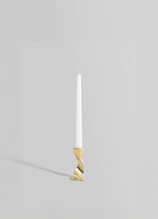 A tall, slender candle holder made of metal with a gold finish, featuring an abstract, twisted design at the base, holding a white taper candle.
