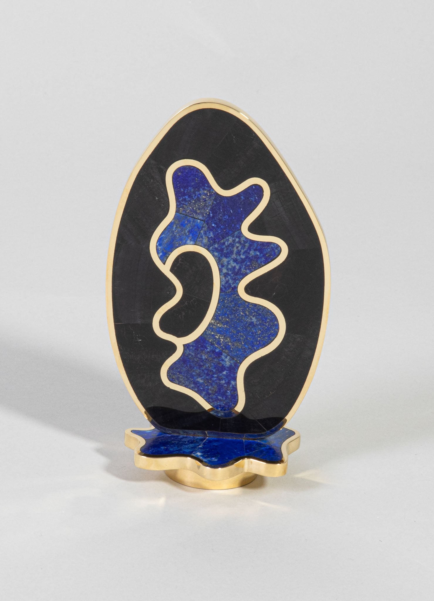 Decorative sculpture with an abstract organic shape featuring blue and gold speckled inlay, set against black stone with gold trim accents. The sculpture stands on a matching blue and gold base, crafted in a contemporary style.