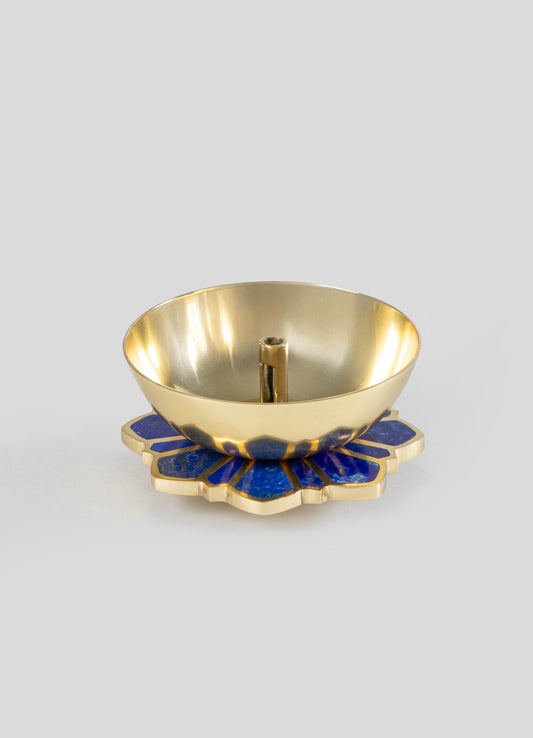 A brass bowl with a polished finish, mounted on a distinctive blue and gold ceramic base with a floral motif, and featuring a central cylindrical holder.