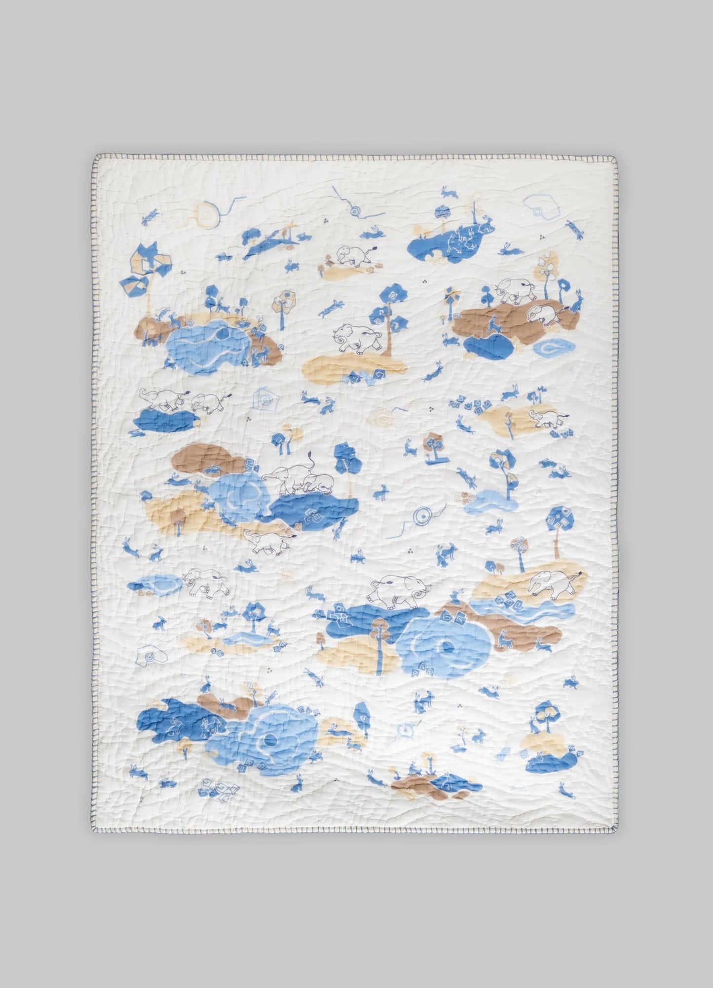 Quilt with a whimsical animal and nature motif in shades of blue and beige on a white background, featuring stitched details and a repeating pattern.