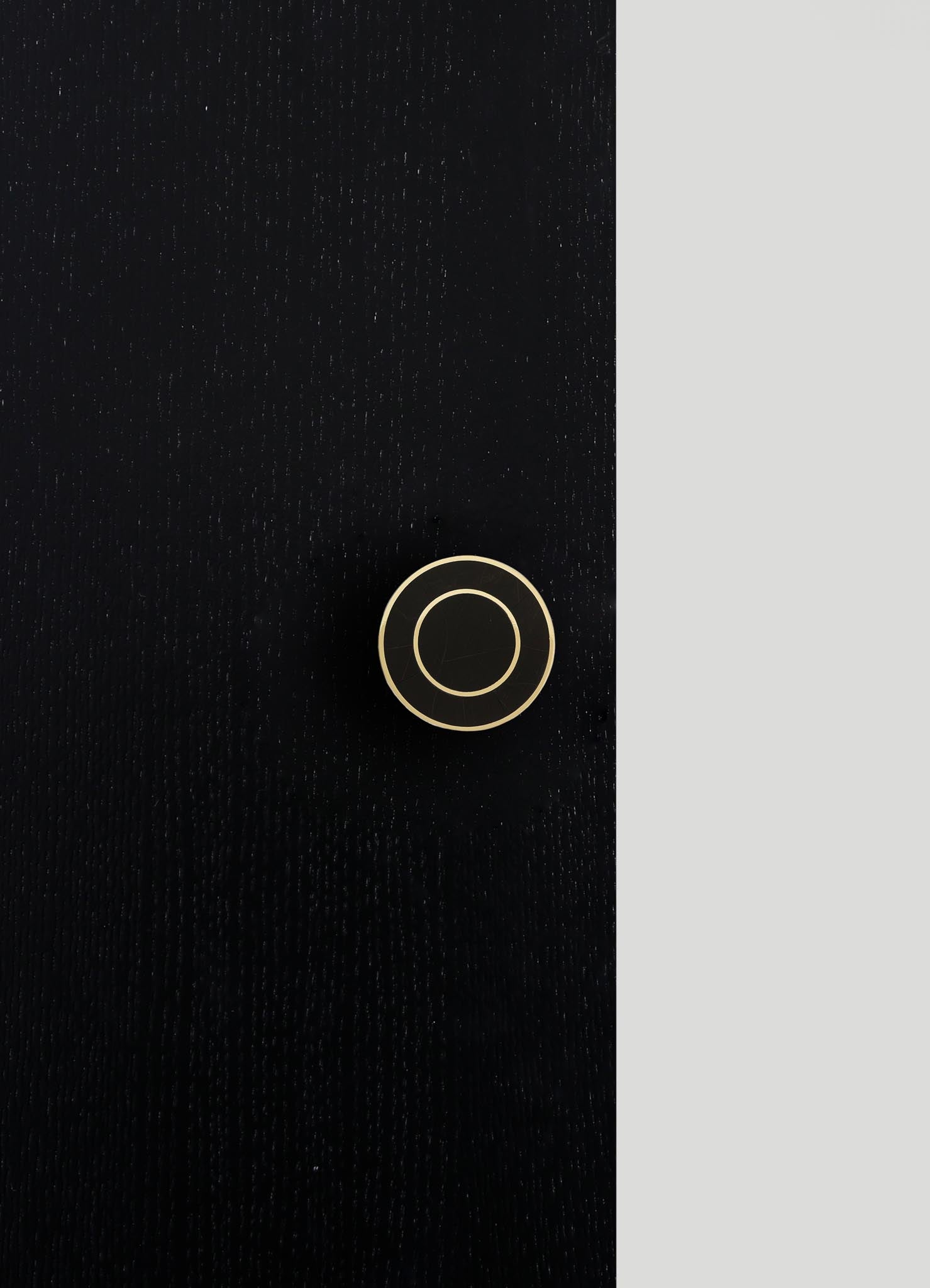A black fabric surface with a subtle textured pattern, featuring a round, minimalist control knob with a metallic finish. The image includes a contrasting light gray area on the right side, emphasizing the sleek design of the control element.