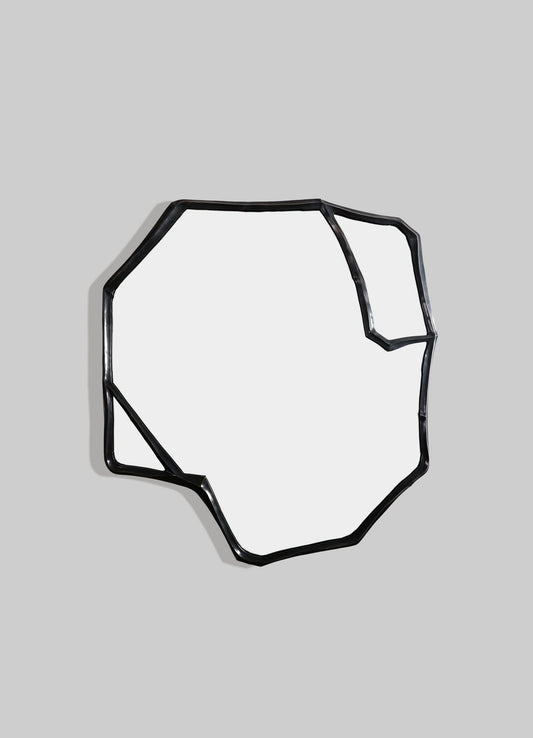 A decorative wall mirror with an irregular, abstract black metal frame, set against a light background. The frame features a minimalist, contemporary style with geometric, angular lines.