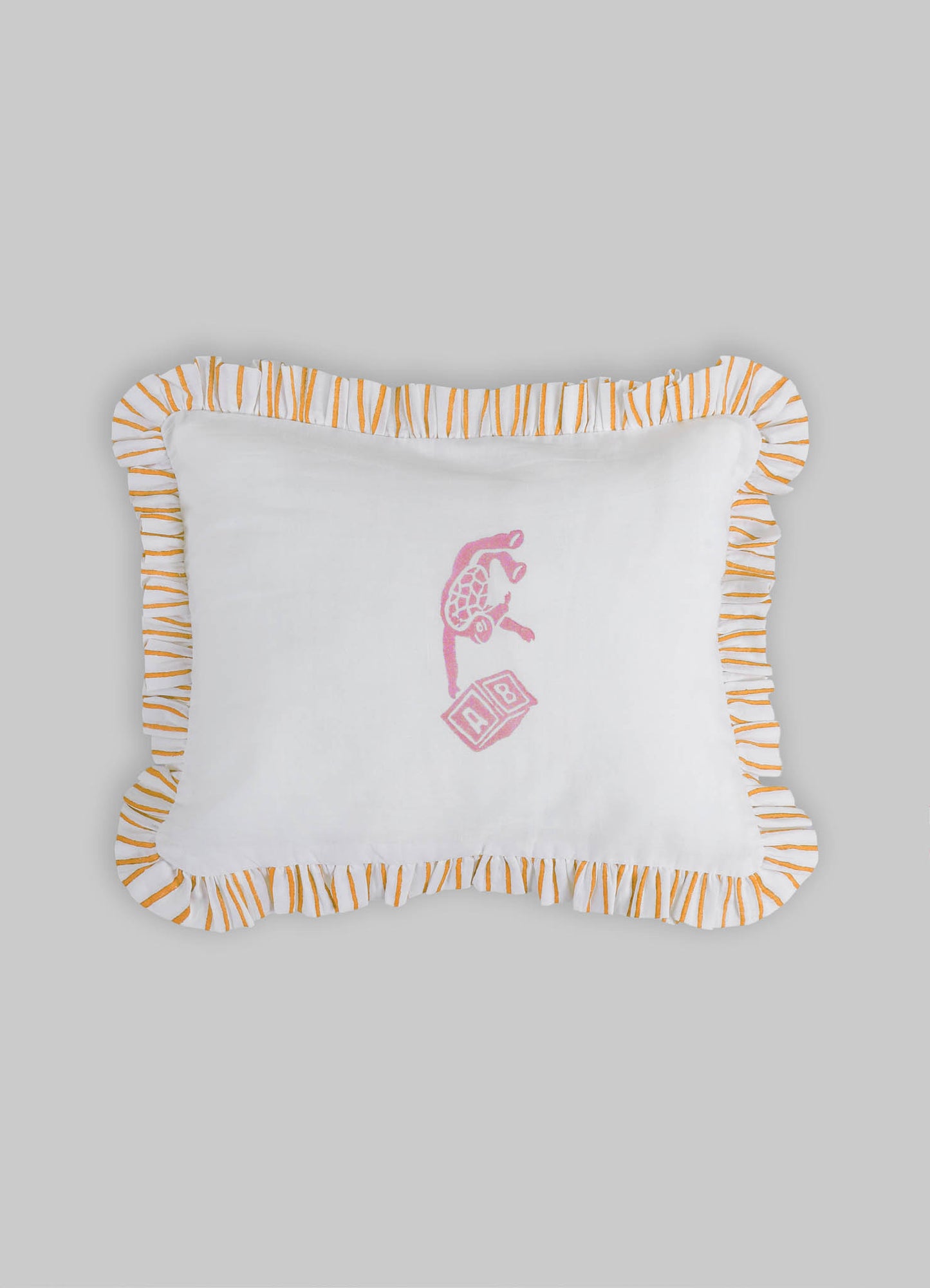 White fabric cushion with orange and white striped ruffled border and pink embroidered giraffe and alphabet block motif.