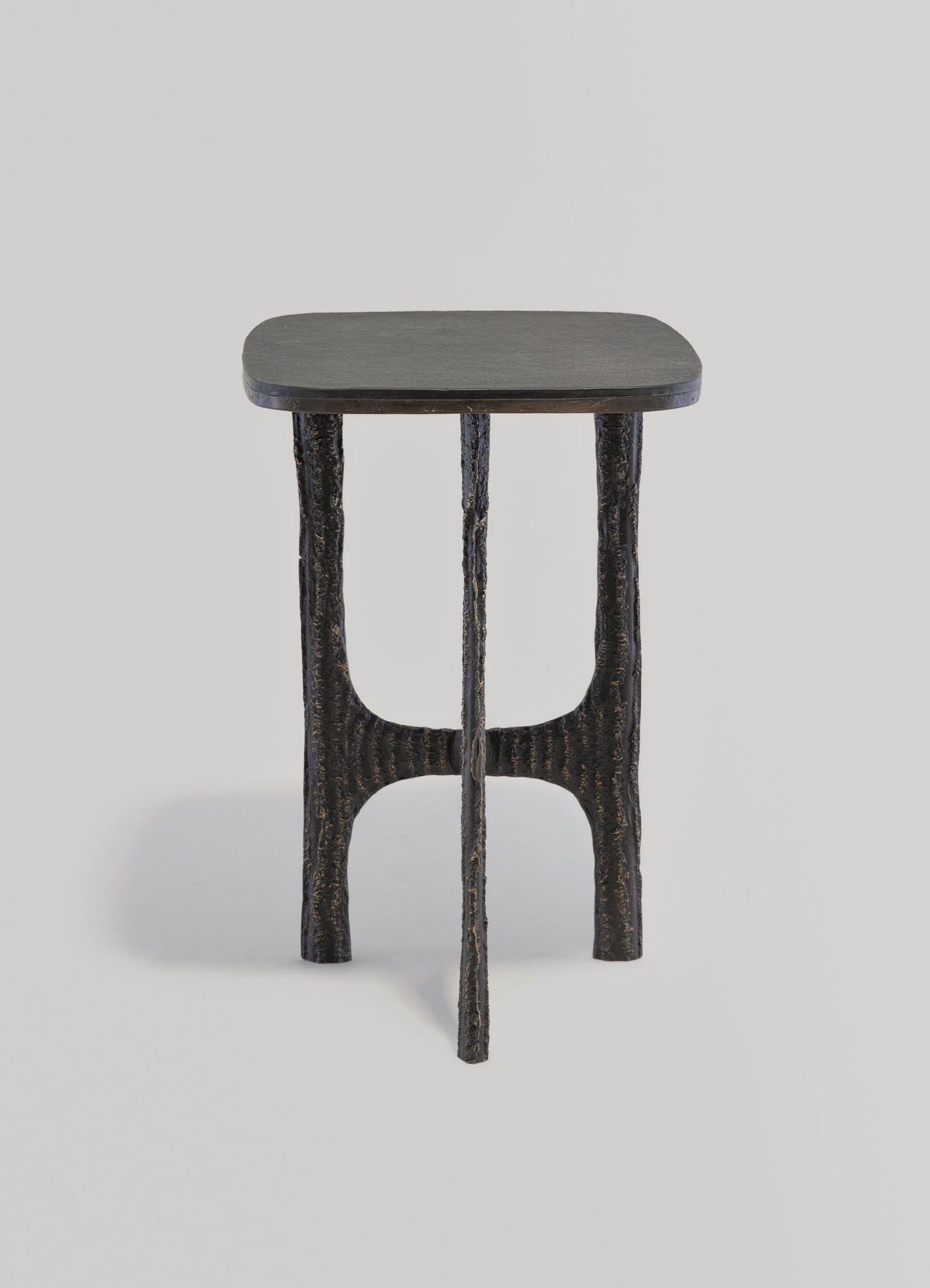 Wooden side table with a dark, textured finish and a rounded rectangular top. The legs are handcrafted, with a rustic, organic shape and a blackened, distressed surface.