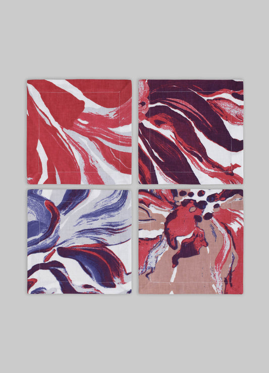 Set of four fabric napkins with abstract floral and watercolor-inspired motifs in shades of red, purple, blue, and beige on white backgrounds. The napkins have a contemporary design with bold, flowing patterns.
