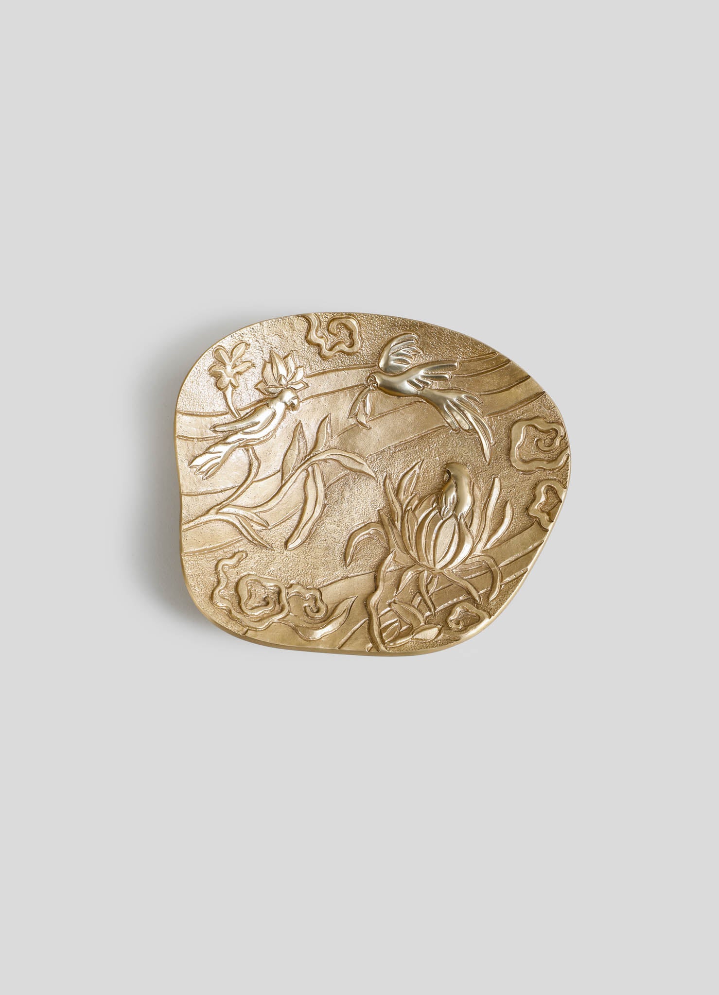 A decorative gold-toned tray with embossed floral and bird motifs, featuring a textured surface and rounded edges, designed in an ornate, handcrafted style.