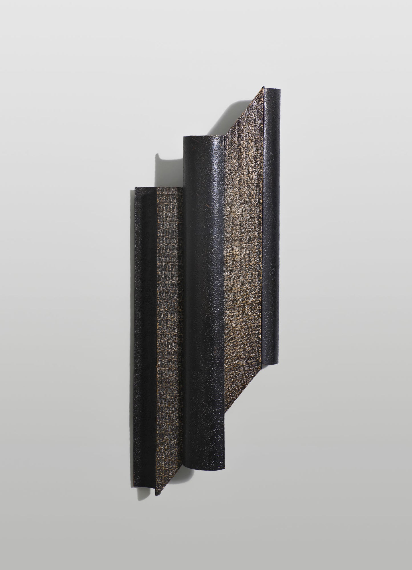 Decorative wall panel with a textured black and metallic gold finish, featuring vertical, curved strips arranged in an abstract modern design.