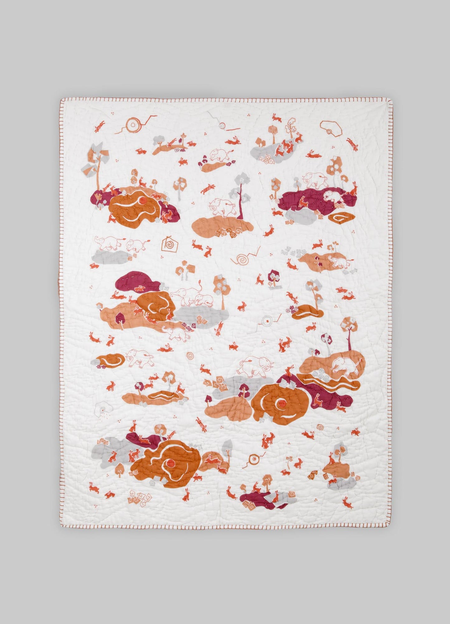 Quilt with an embroidered animal motif pattern featuring elephants and foliage in shades of white, orange, burgundy, and gray. Made from a soft textile material, displayed flat against a gray background.