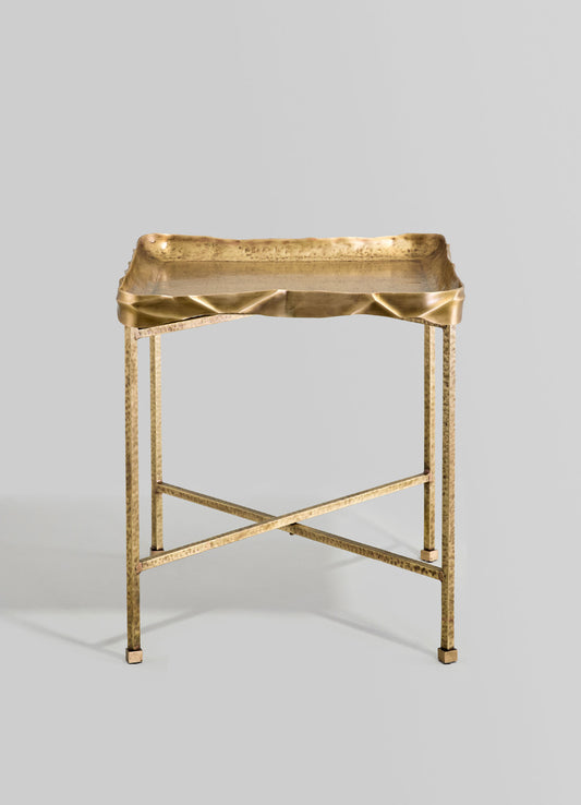 Brass serving tray with a textured, hammered surface and slightly raised edges, supported by a matching brass stand with a cross-brace design.