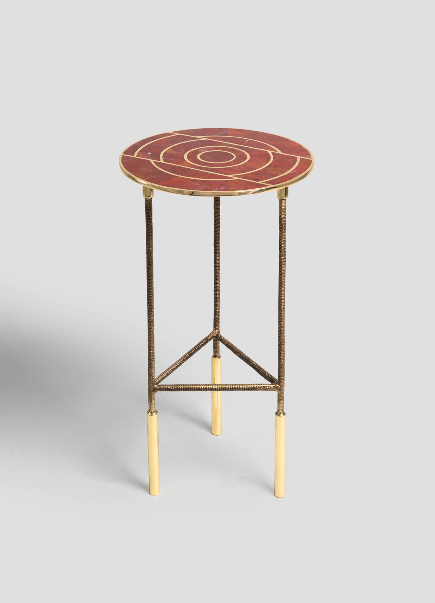 A small side table with a round marble top featuring a red and gold geometric pattern, supported by a metal frame with brass finish legs and brass accents.