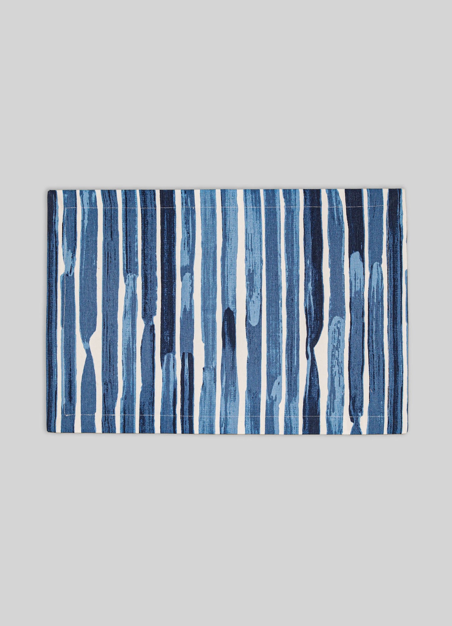 A rectangular table runner with a blue and white vertical stripe pattern, featuring varying shades of blue and a textured, painterly design, set against a light grey background.