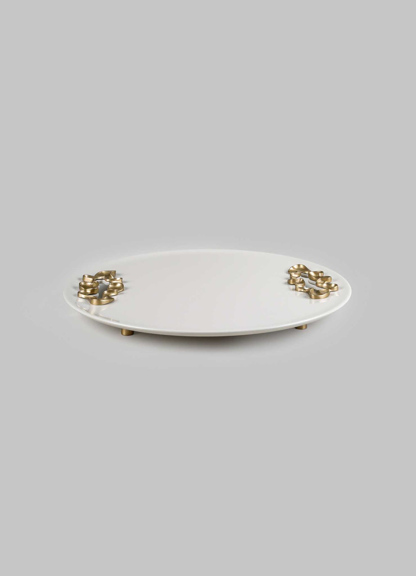 A round ceramic tray with a smooth white finish and metallic gold accents on the edges, supported by small gold-toned feet.
