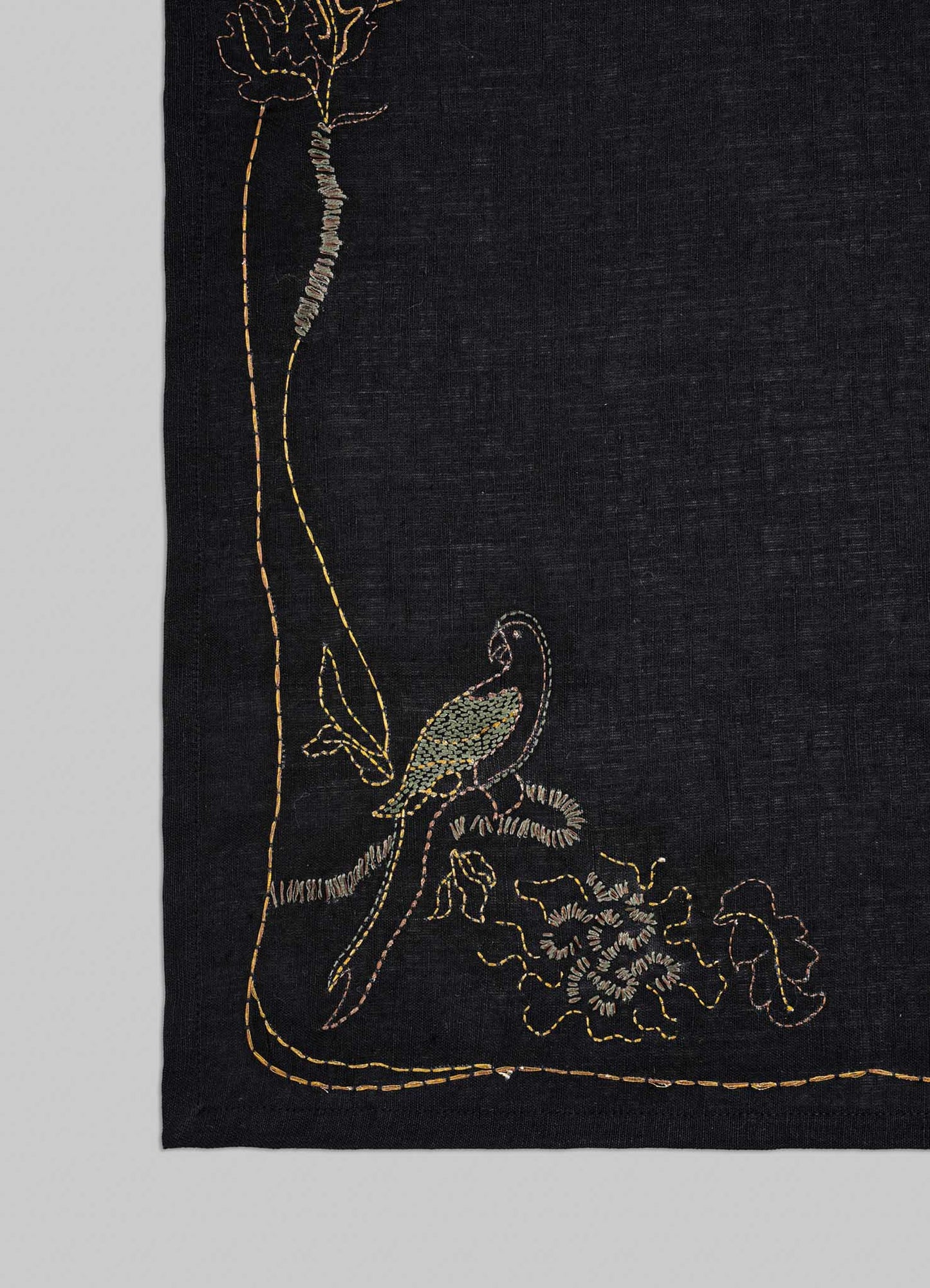 Embroidered fabric with a bird and floral design on a black background viya luxury placemats
