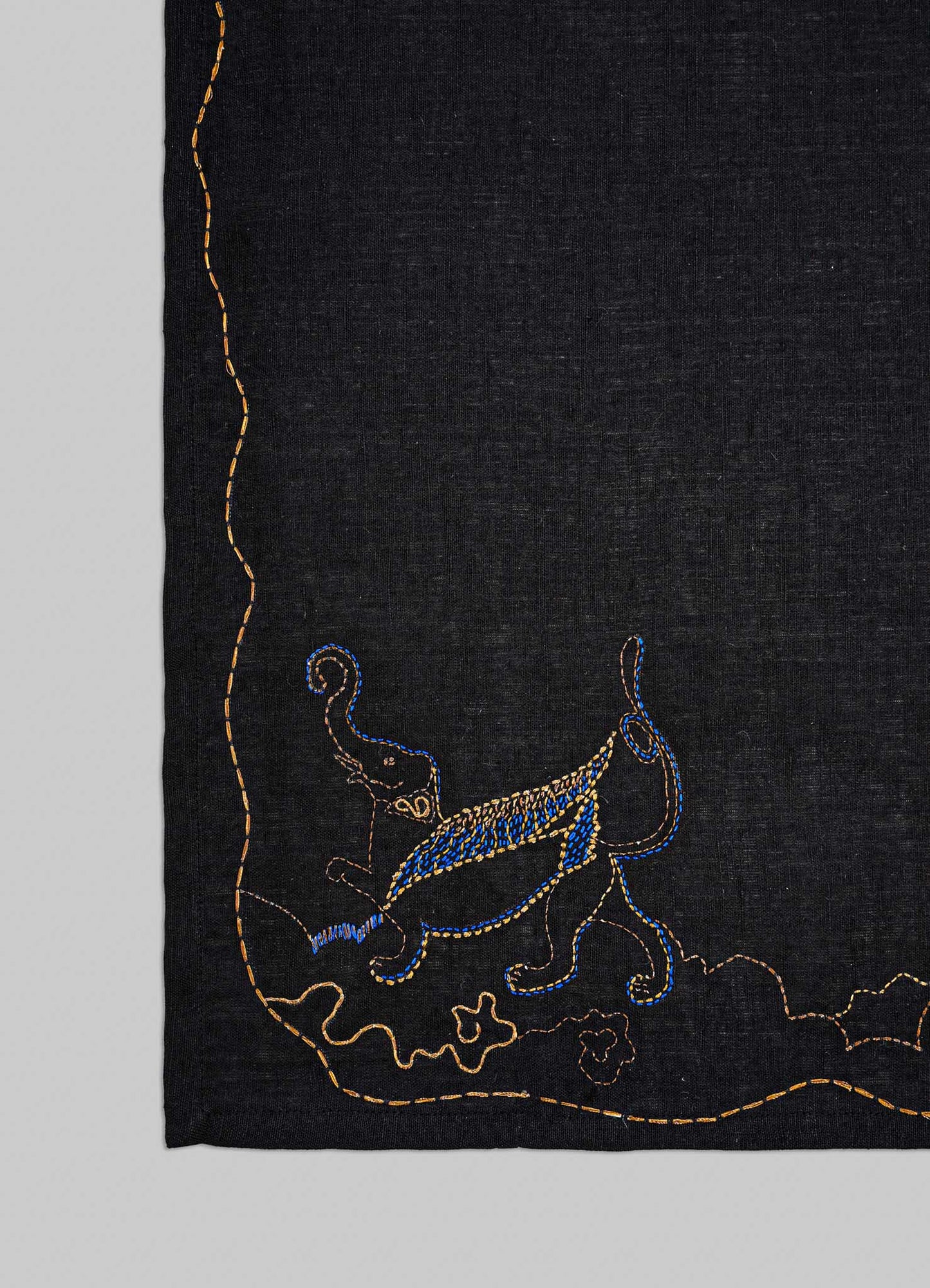 Embroidered design on a black fabric with blue and gold elements viya placemats