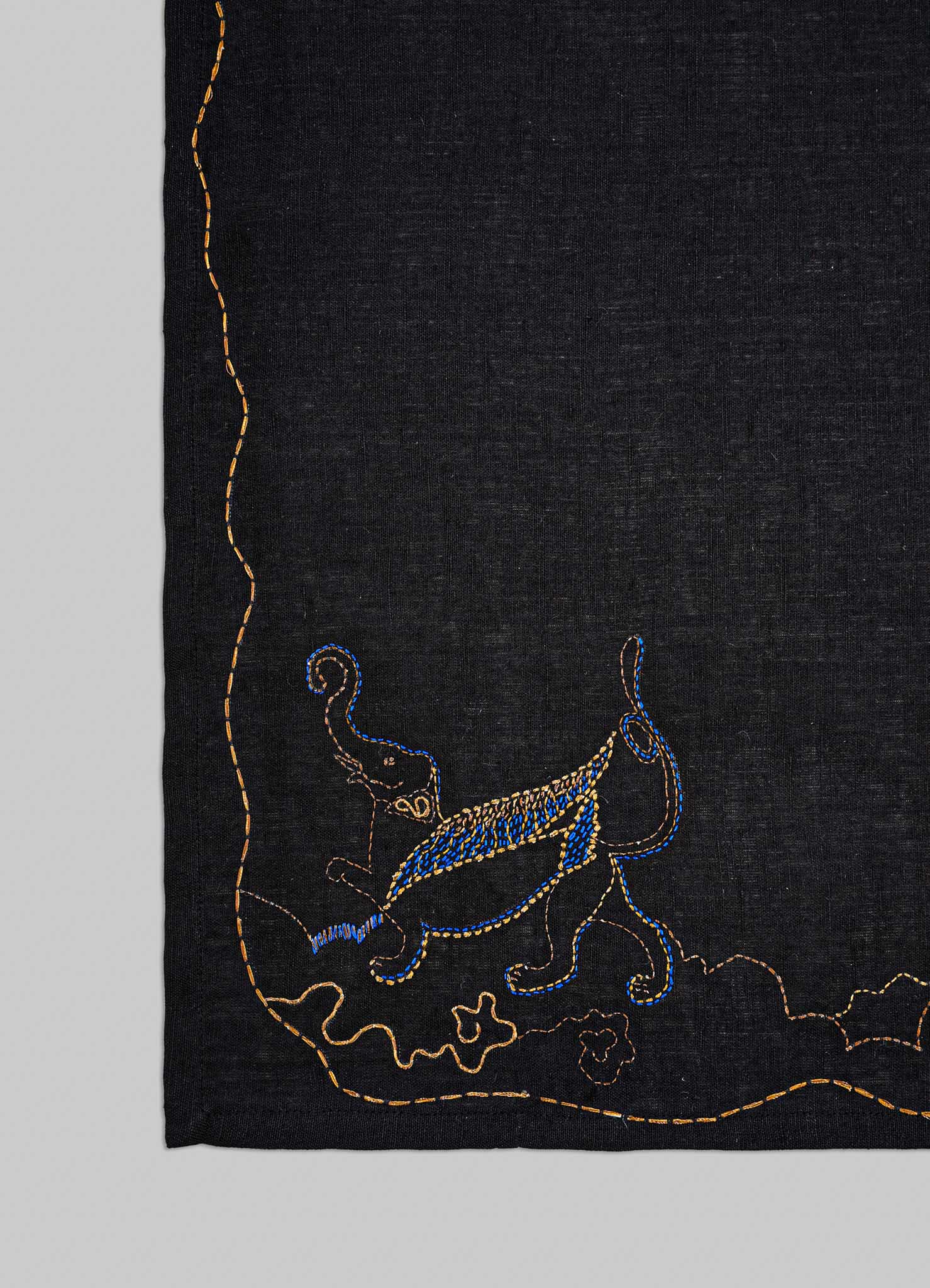 Embroidered design on a black fabric with blue and gold elements viya placemats