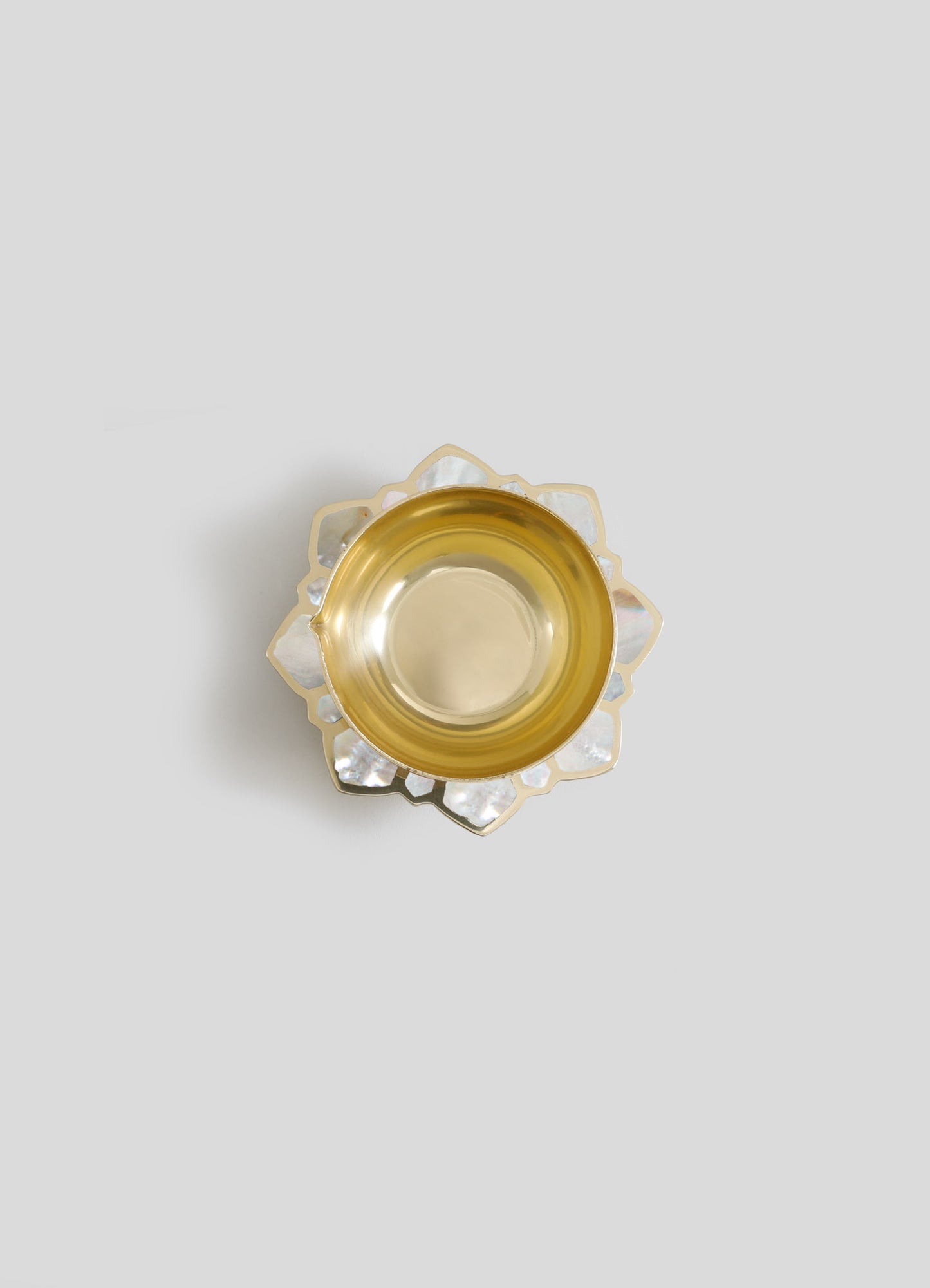 A decorative glass bowl with a gold-tinted interior and a scalloped edge made of iridescent shell-shaped panels, set against a plain light background.