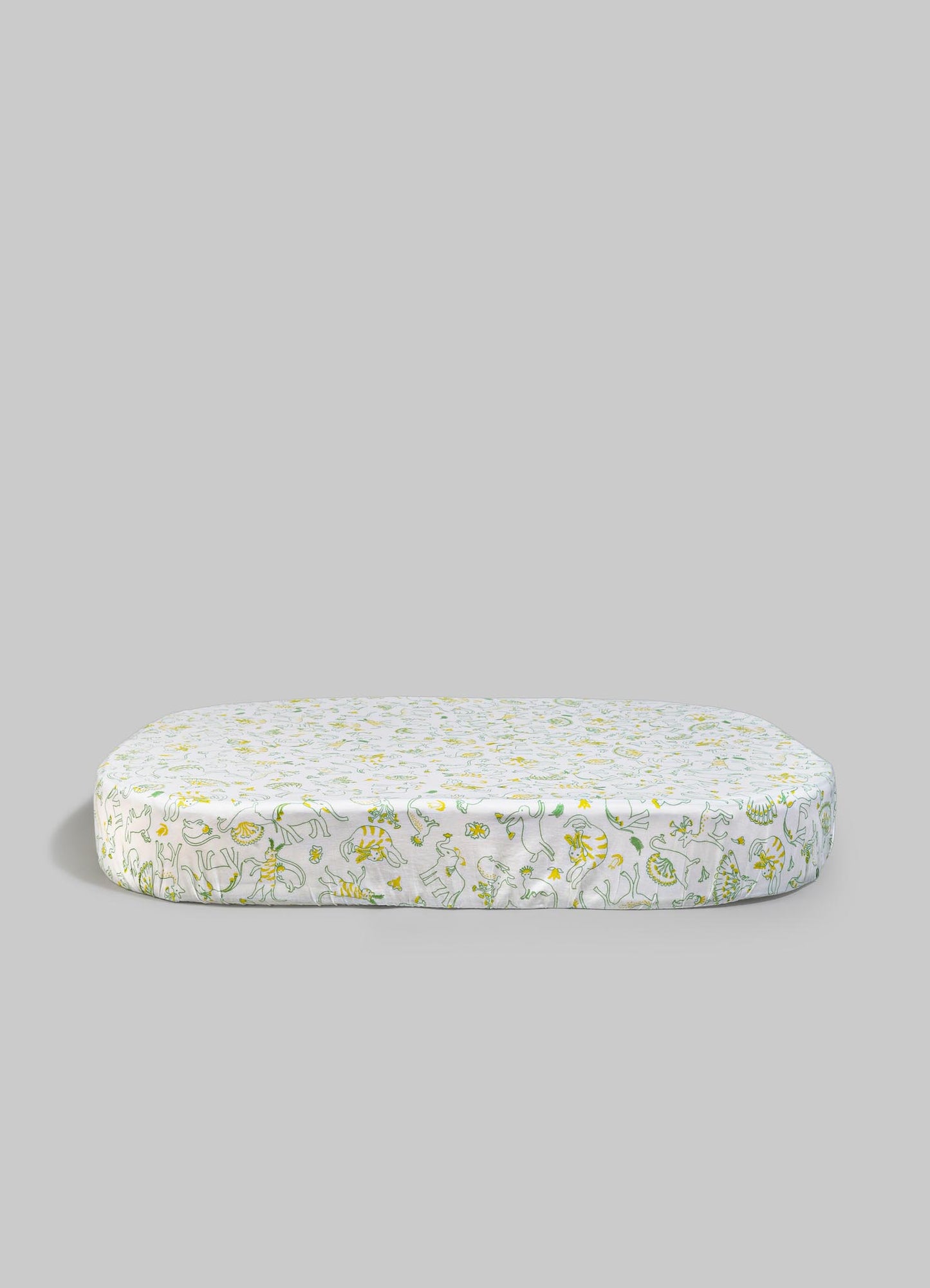 Printed fabric cushion with a playful animal and floral motif in yellow and green on a white background, with a soft, padded appearance.