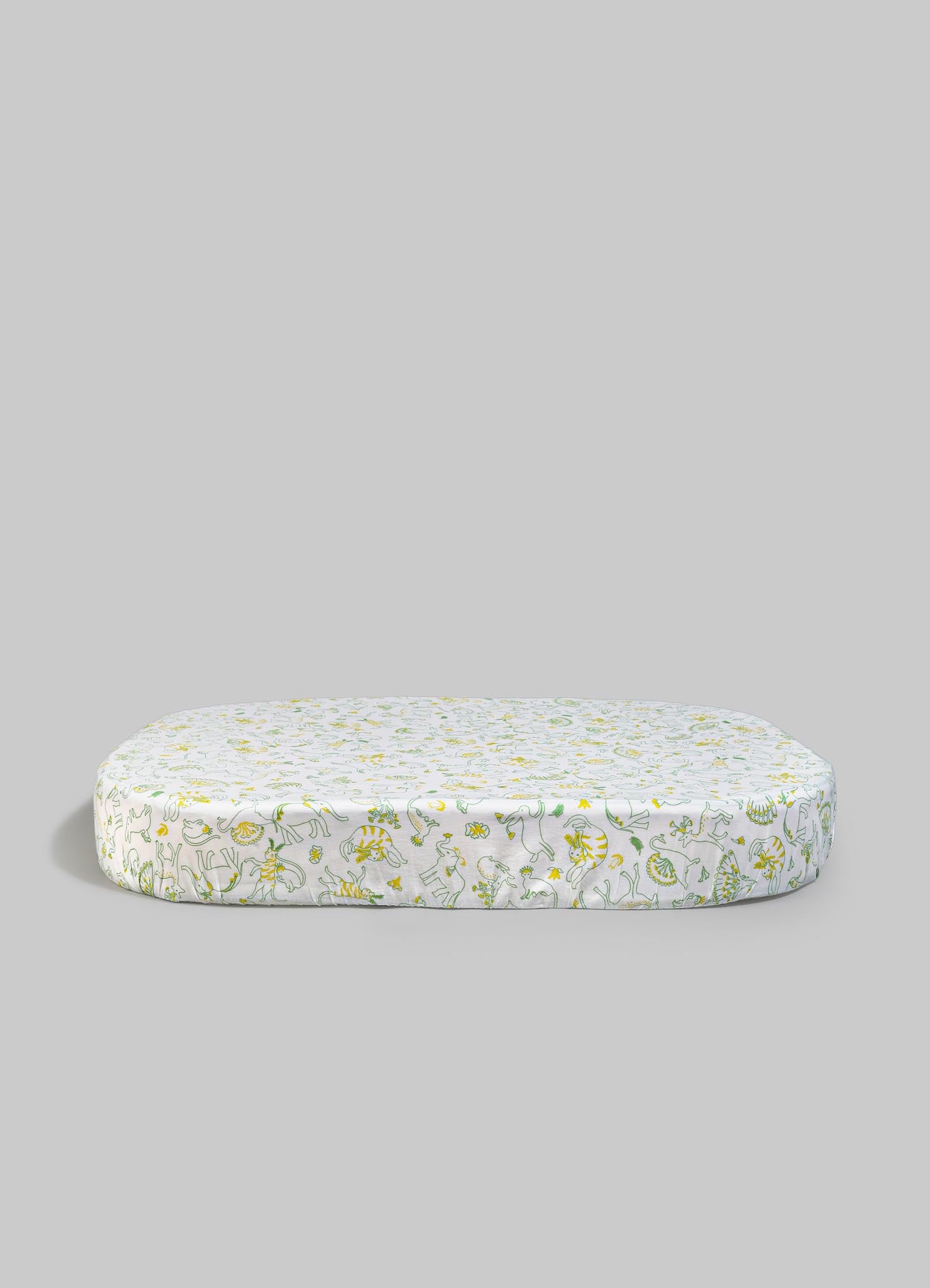Printed fabric cushion with a playful animal and floral motif in yellow and green on a white background, with a soft, padded appearance.