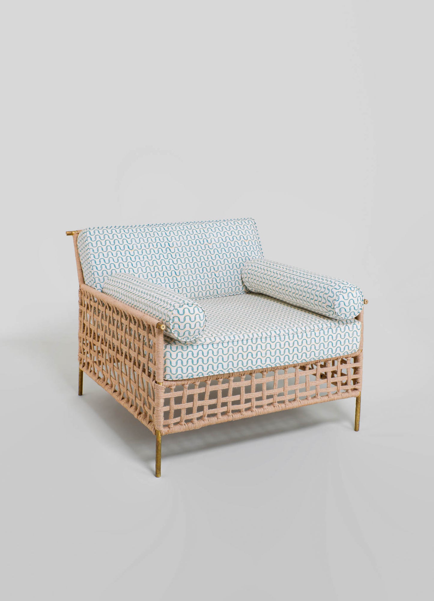 A small sofa with a woven rattan frame and metal legs, upholstered with fabric that features a blue and white geometric pattern. The design combines natural materials with a contemporary style.