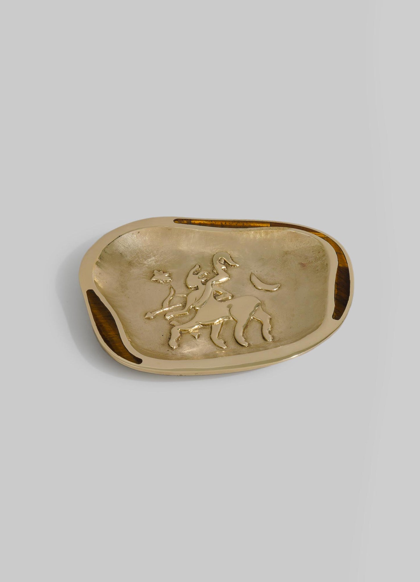 A decorative ceramic dish featuring a gold-toned interior with an embossed lion motif, edged with dark wood accents on the rim, in a contemporary style.