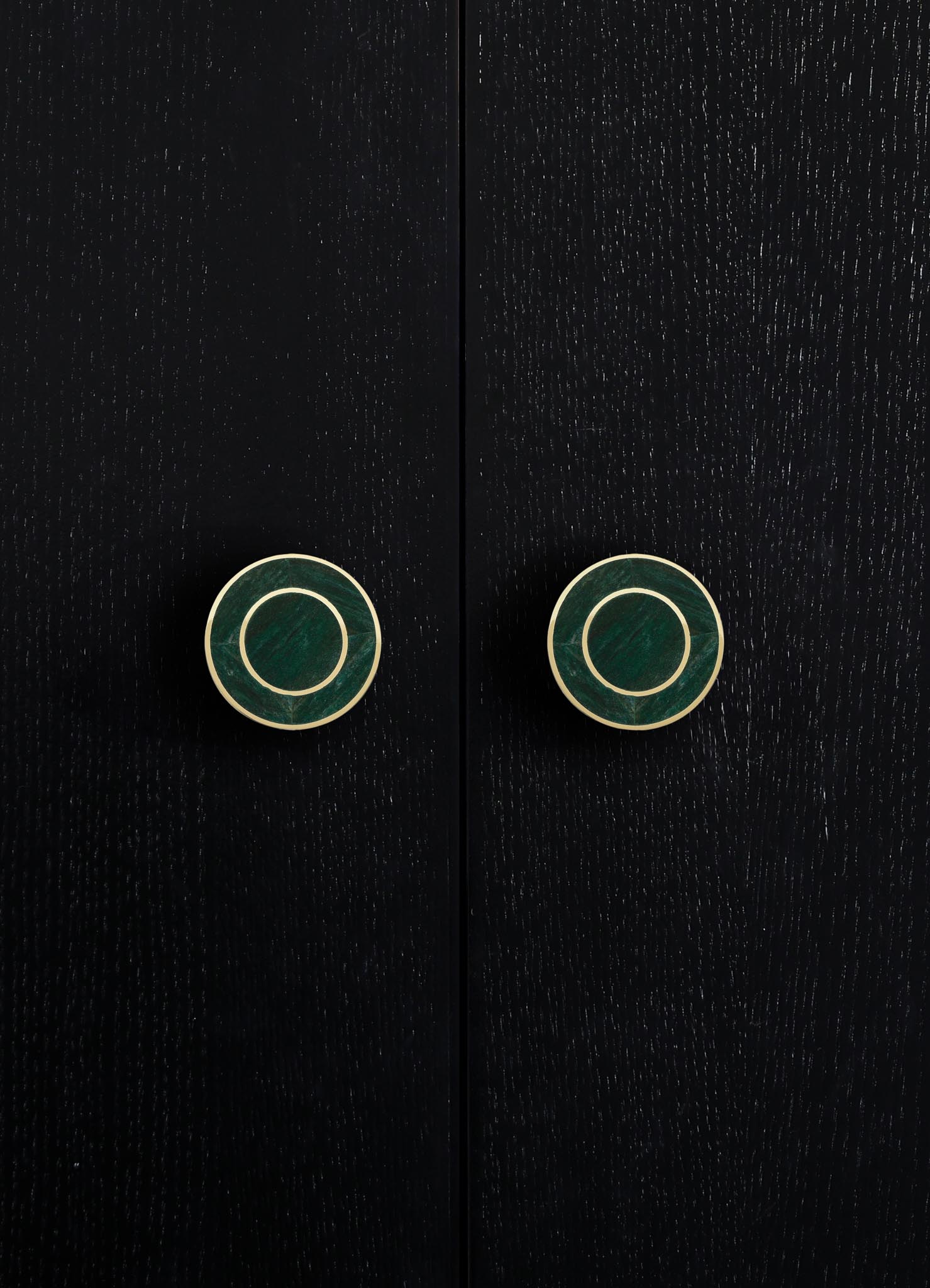 Black wooden cabinet with textured surface and round metallic gold and green drawer pulls. The style appears contemporary with a sleek, minimalist design.
