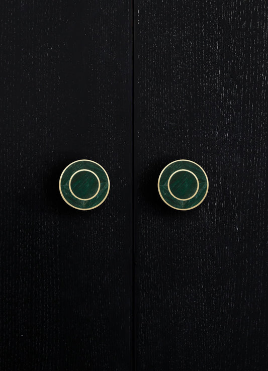 Black wooden cabinet with textured surface and round metallic gold and green drawer pulls. The style appears contemporary with a sleek, minimalist design.