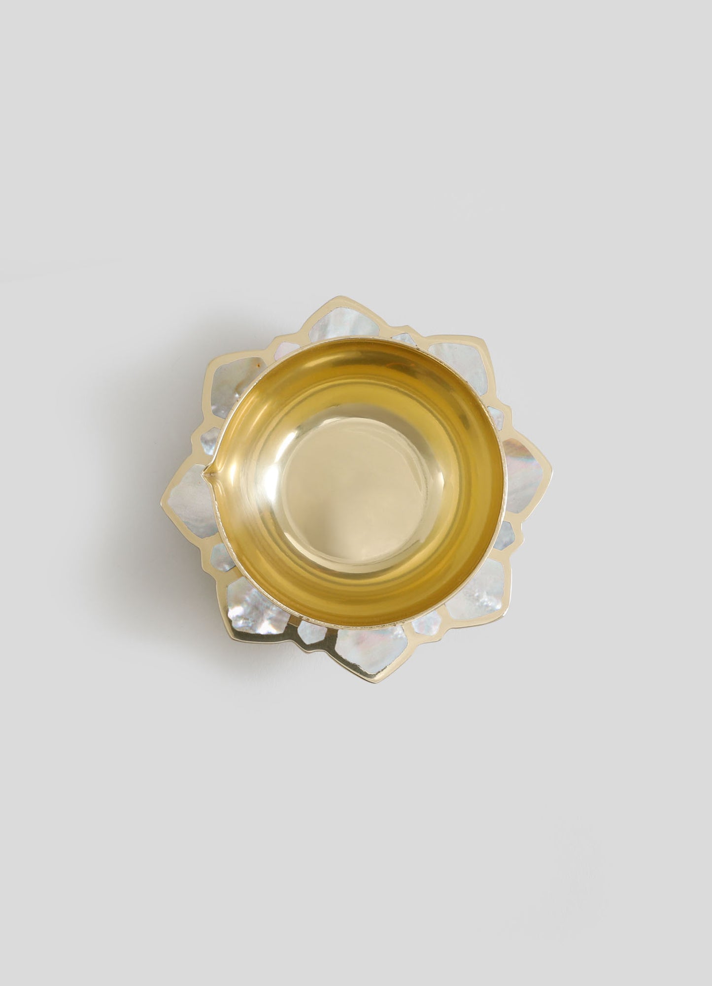 A decorative glass bowl with a gold-toned interior and an irregularly shaped, iridescent shell-patterned rim.