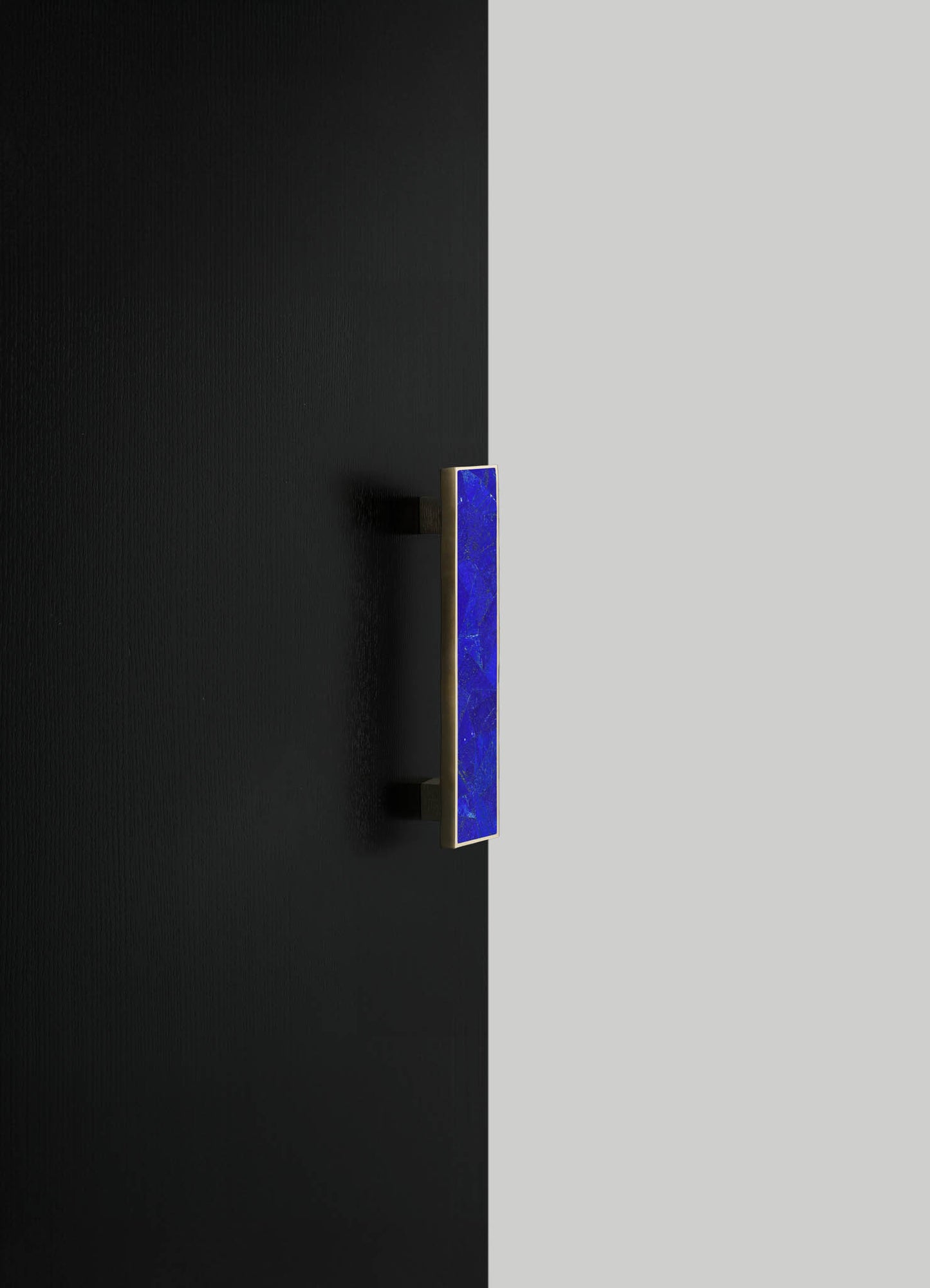 A contemporary wall-mounted light fixture with a rectangular blue glass shade and a metallic finish, installed on a black wall. The design features clean lines and a minimalist aesthetic.