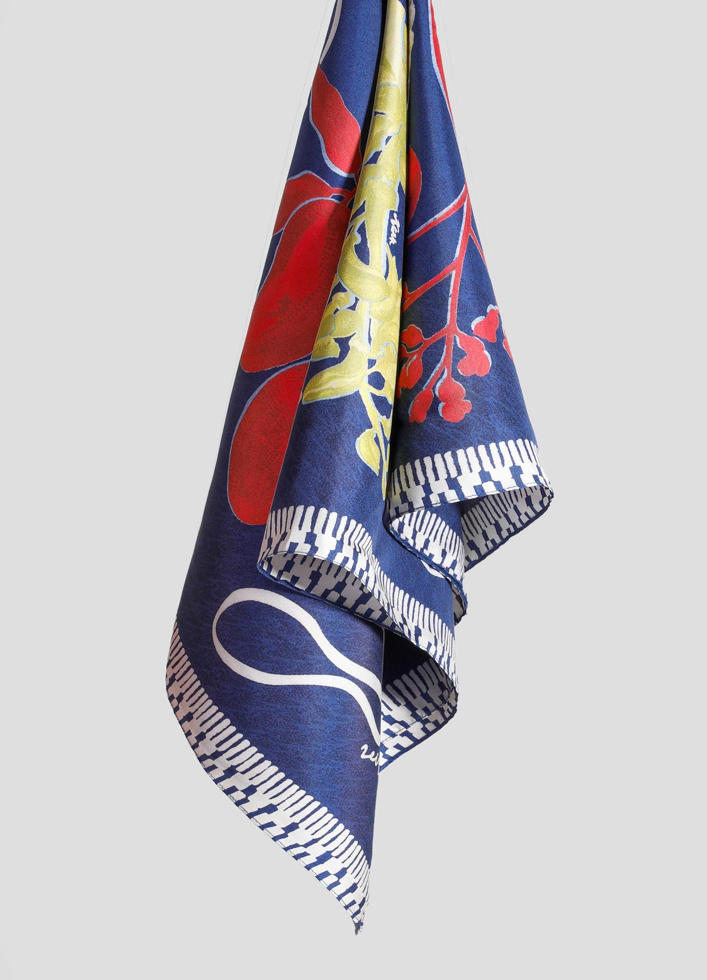 A fabric towel with a floral pattern in bold red, yellow, and blue colors, featuring a geometric border design.