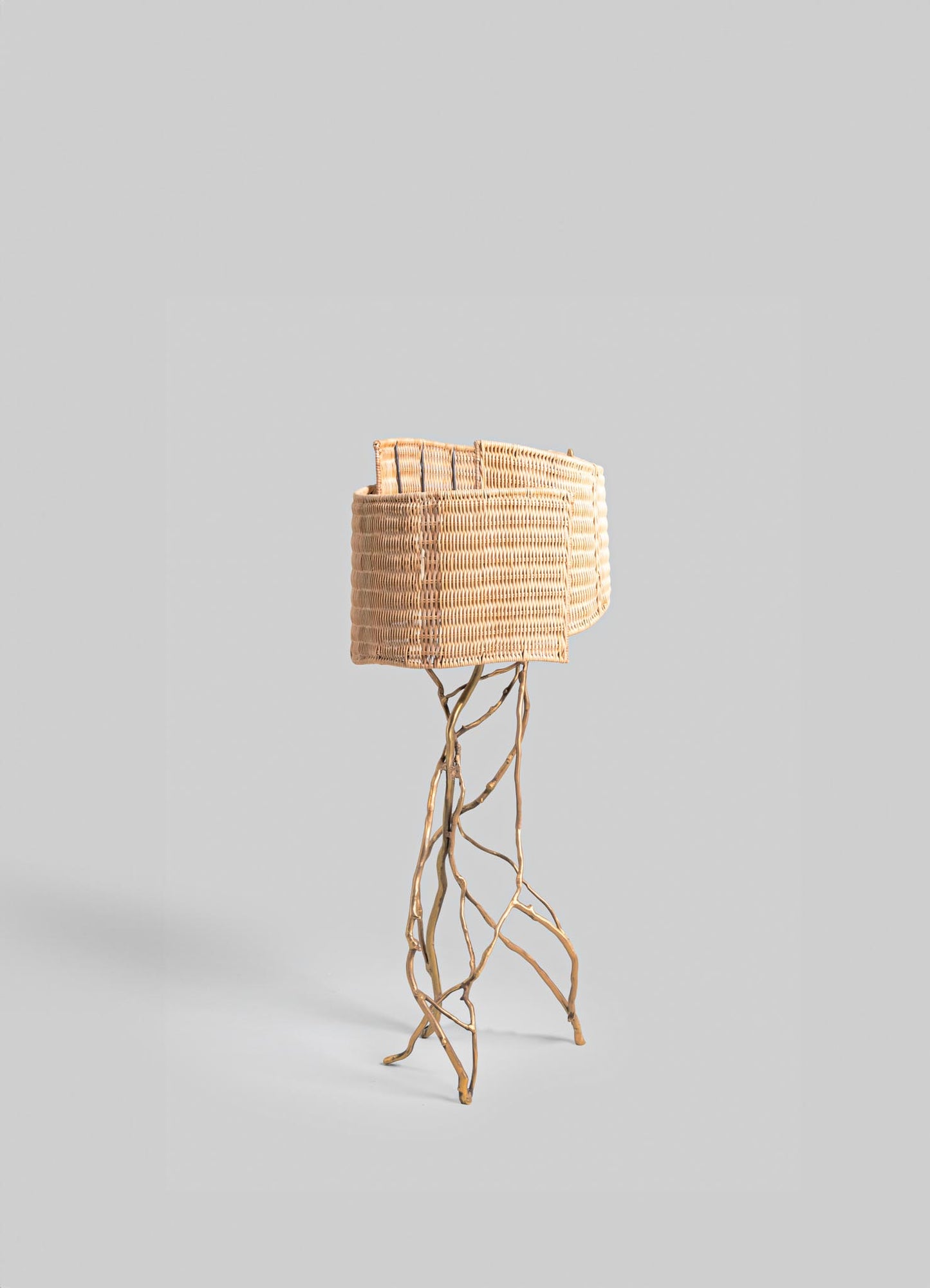 Wicker floor lamp with a woven shade and a base made of intertwined natural wood branches, showcasing a rustic and organic style.