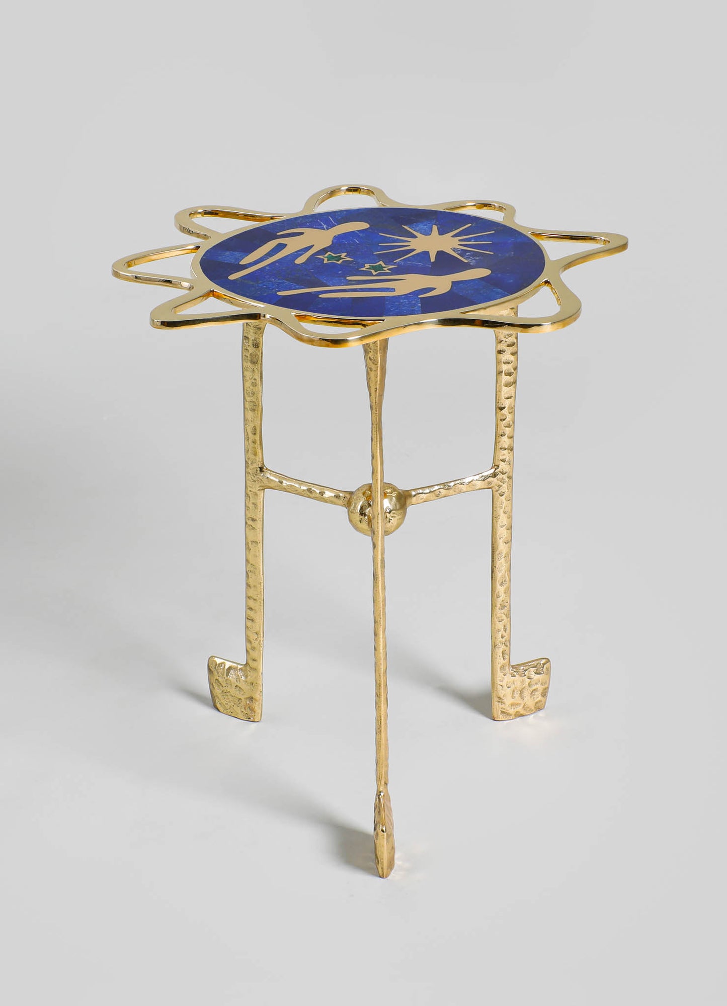 A decorative side table with a gold-colored metal frame and textured legs, featuring a circular blue surface with celestial motifs, including stars and abstract designs. The design style combines contemporary and luxurious elements with a focus on metallic accents and artistic motifs.