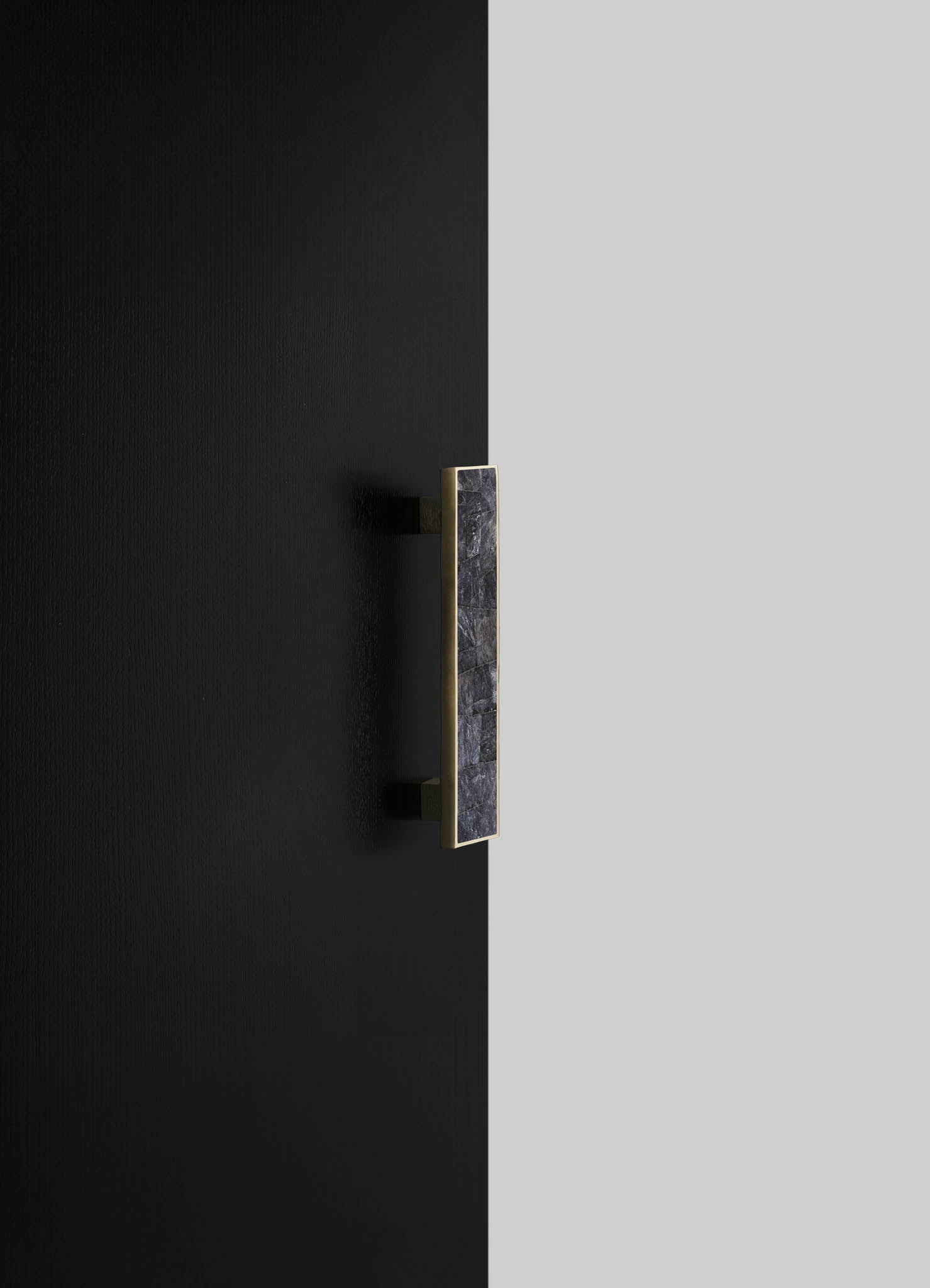 A modern wall sconce with a rectangular black marble shade framed in gold, mounted on a textured black wall. The design combines luxury materials with minimalist geometric elements for contemporary interior decor.