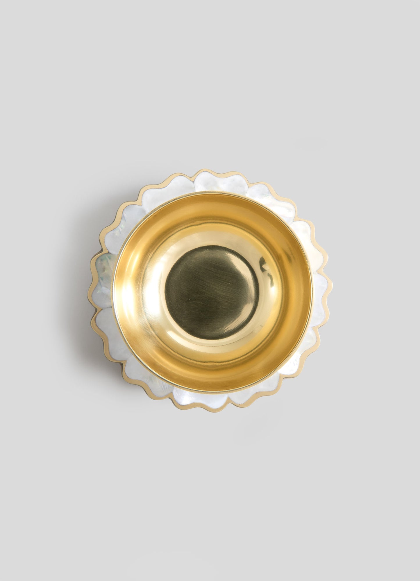 A decorative bowl with a layered design, featuring a shiny gold interior and a white, scalloped edge with gold trim. The bowl combines metallic and ceramic materials, emphasizing a luxurious and elegant style.