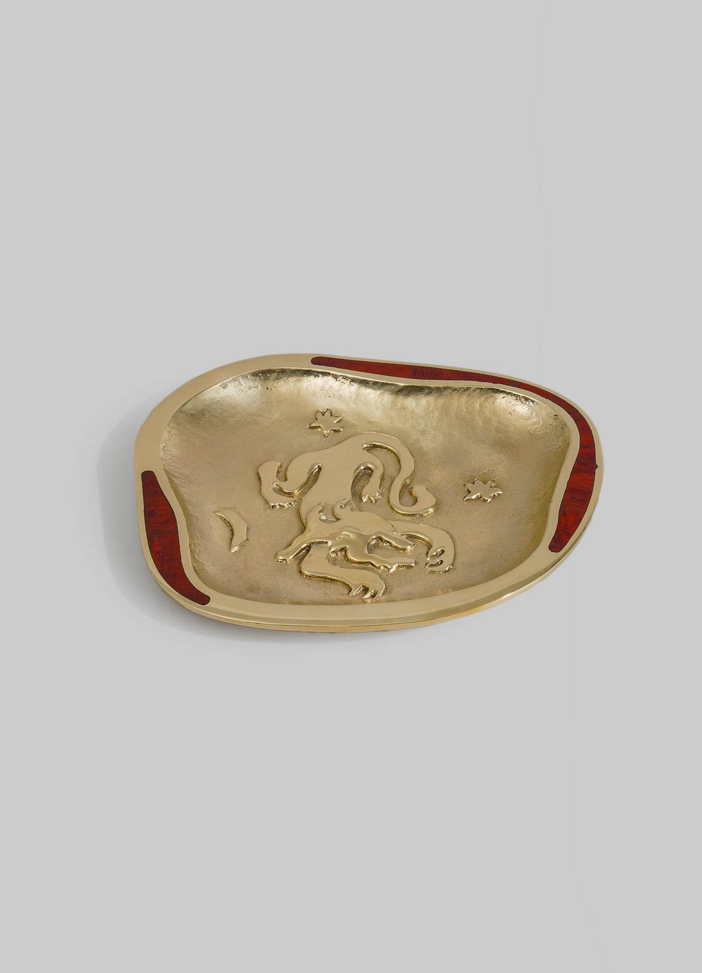 A decorative tray with a gold-toned interior and red accents on the edges, featuring an embossed dragon motif and star-shaped details. The tray has an irregular oval shape and a smooth, glossy finish.