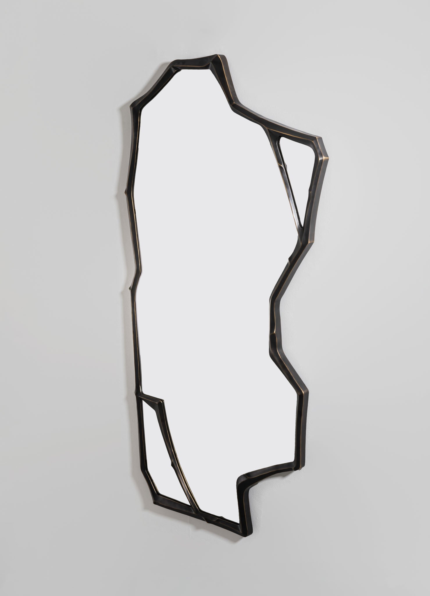 A decorative wall mirror with an irregular, geometric black metal frame, mounted on a light-colored wall. The frame features an artistic, contemporary design with uneven, angular lines.