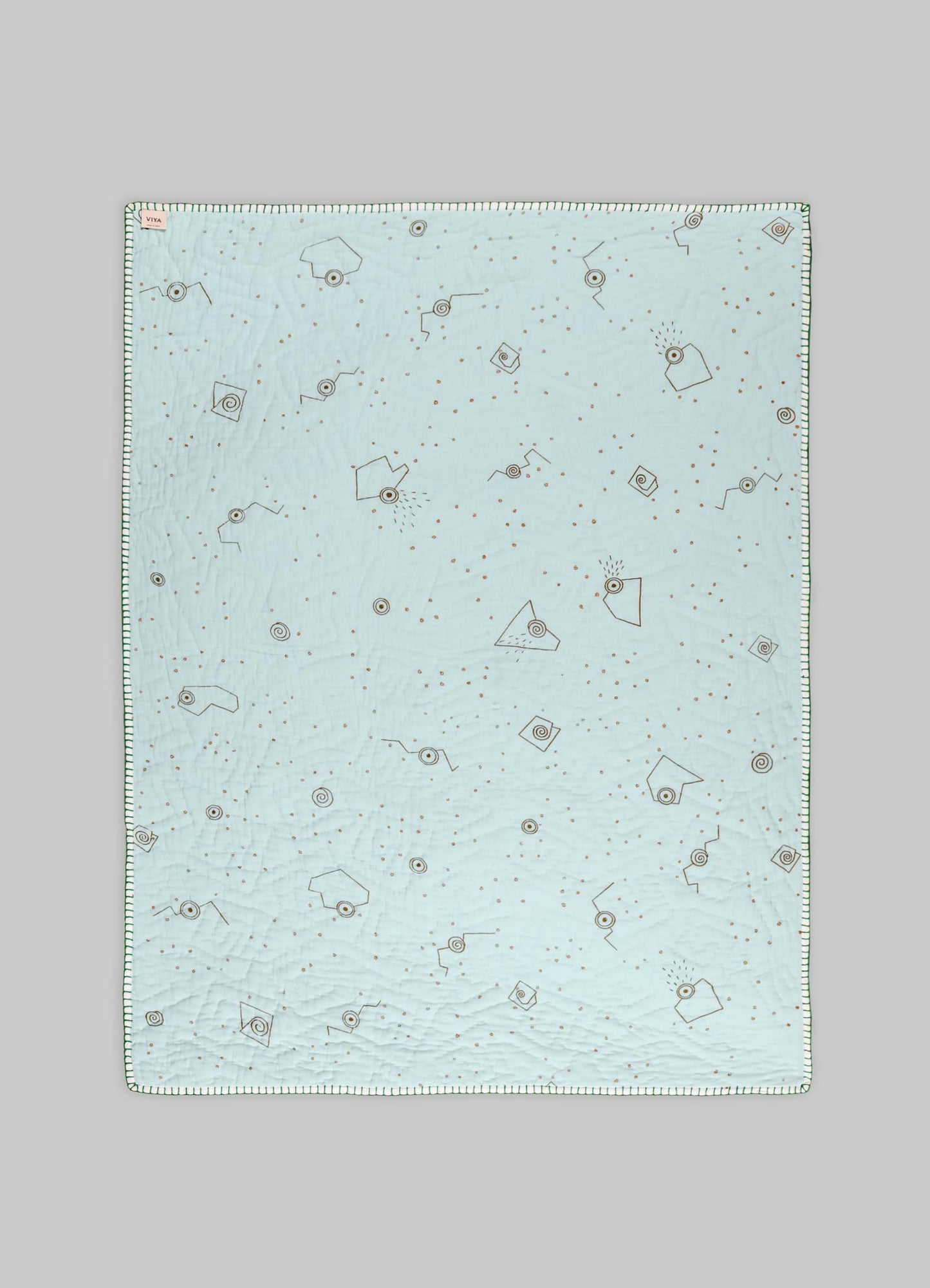 Quilt with a light pastel blue cotton fabric featuring geometric and abstract motifs in brown and black, finished with a striped edge border.