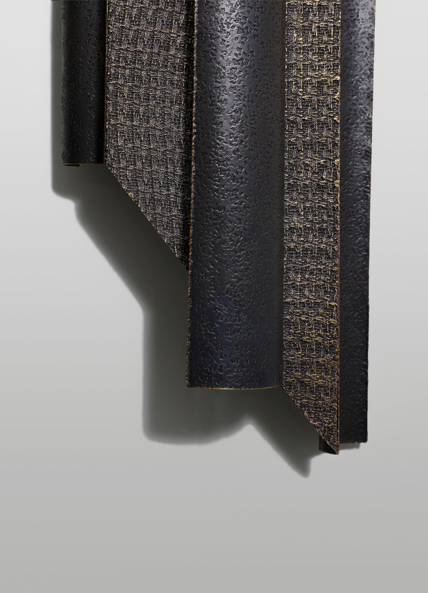 A close-up of a textured black and brown wooden panel with a raised, carved design, featuring a matte finish and sharp angled edges. The surface displays a combination of rough and smooth patterns, emphasizing handcrafted craftsmanship and contemporary style.