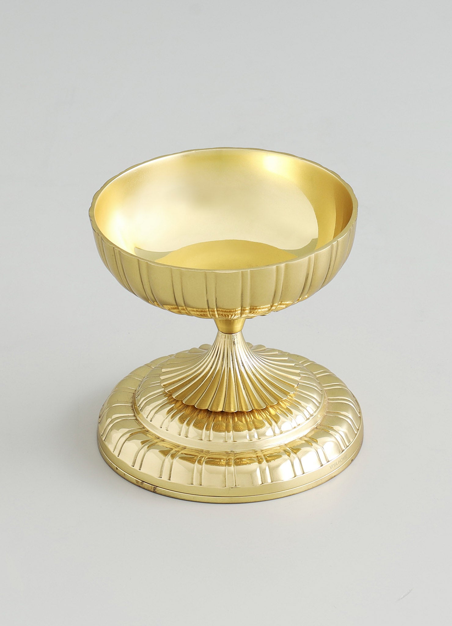 A gold-plated decorative bowl with a fluted design, featuring a smooth, reflective interior and a wide, circular base. The piece has a vintage style with ornate detailing and a polished finish.
