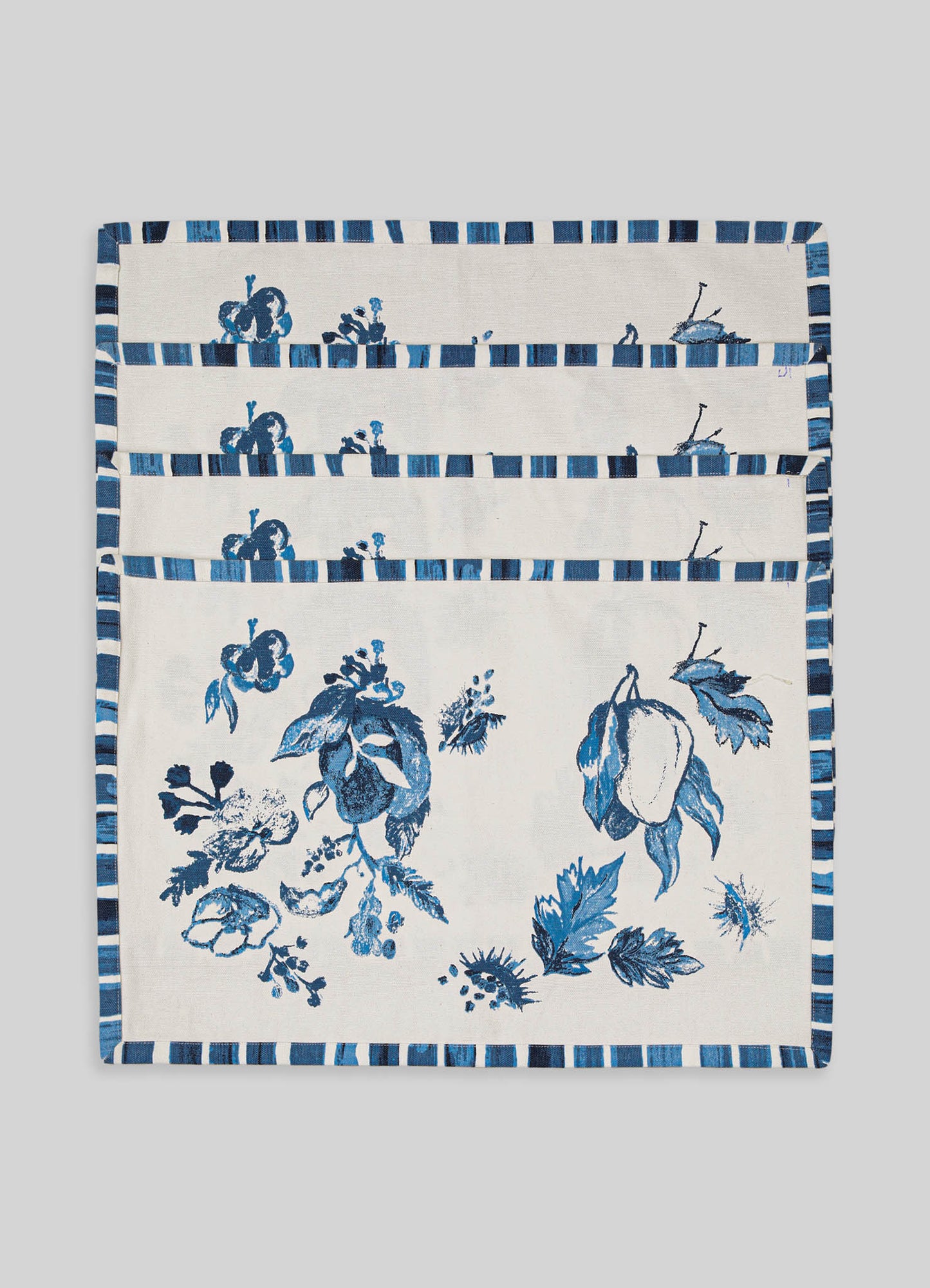 Cotton placemats with a blue floral and leaf pattern, featuring a striped border in shades of blue and white. The design is contemporary with a handcrafted appearance.