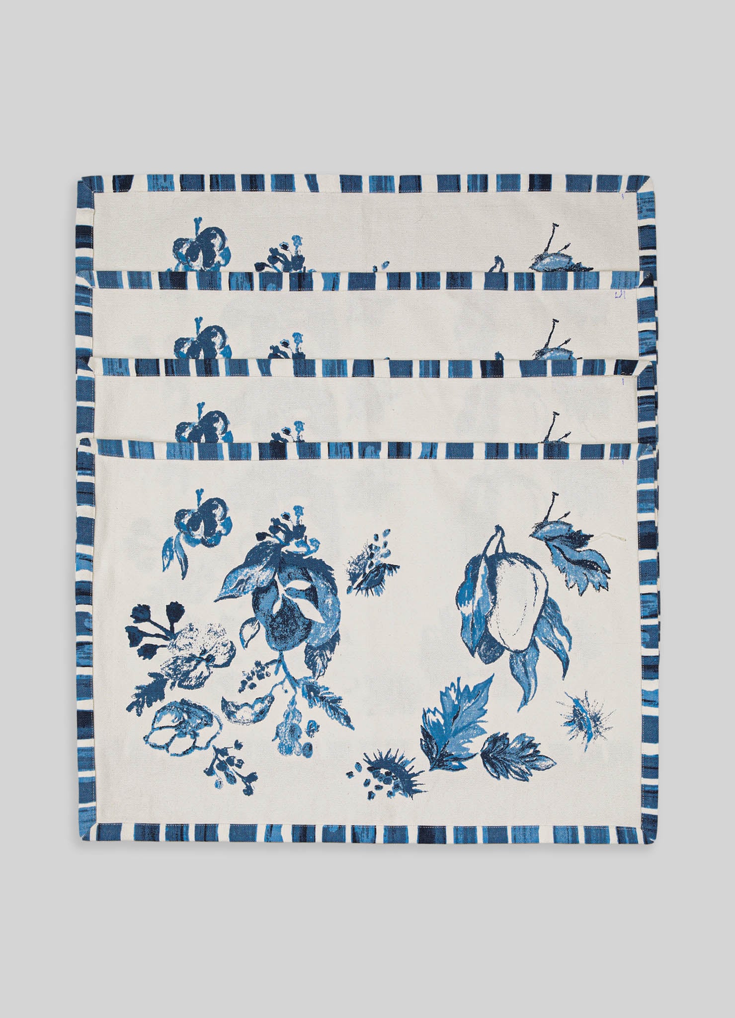 Cotton placemats with a blue floral and leaf pattern, featuring a striped border in shades of blue and white. The design is contemporary with a handcrafted appearance.