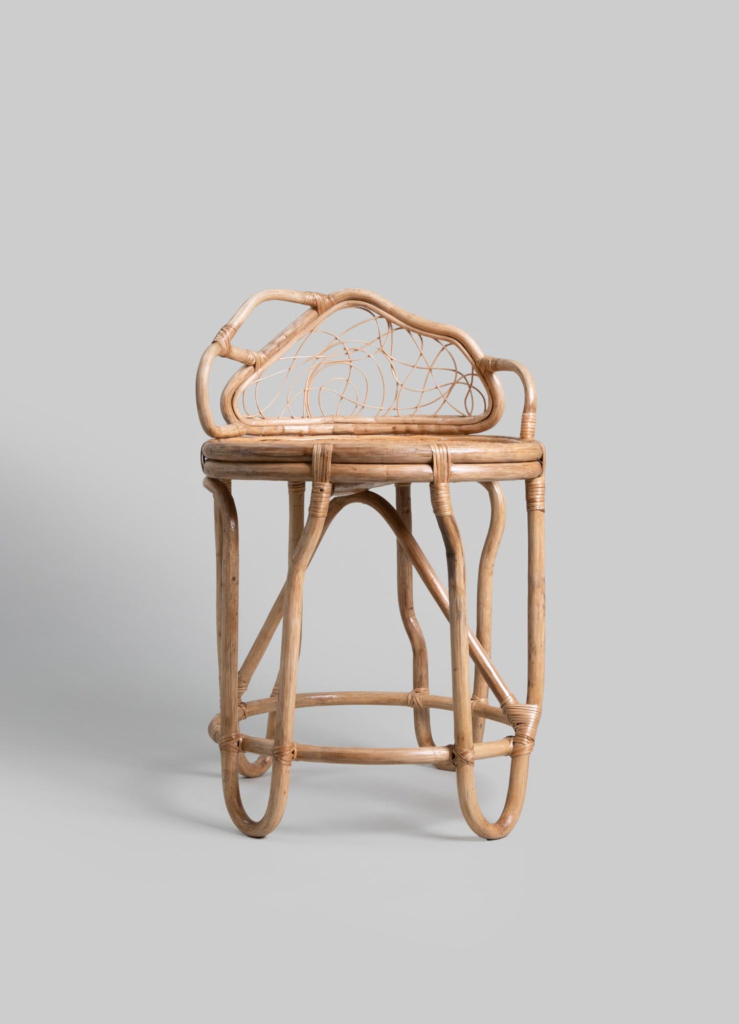 A wooden stool with curved legs and a woven rattan backrest featuring a floral motif, crafted from natural light-toned wood and rattan.