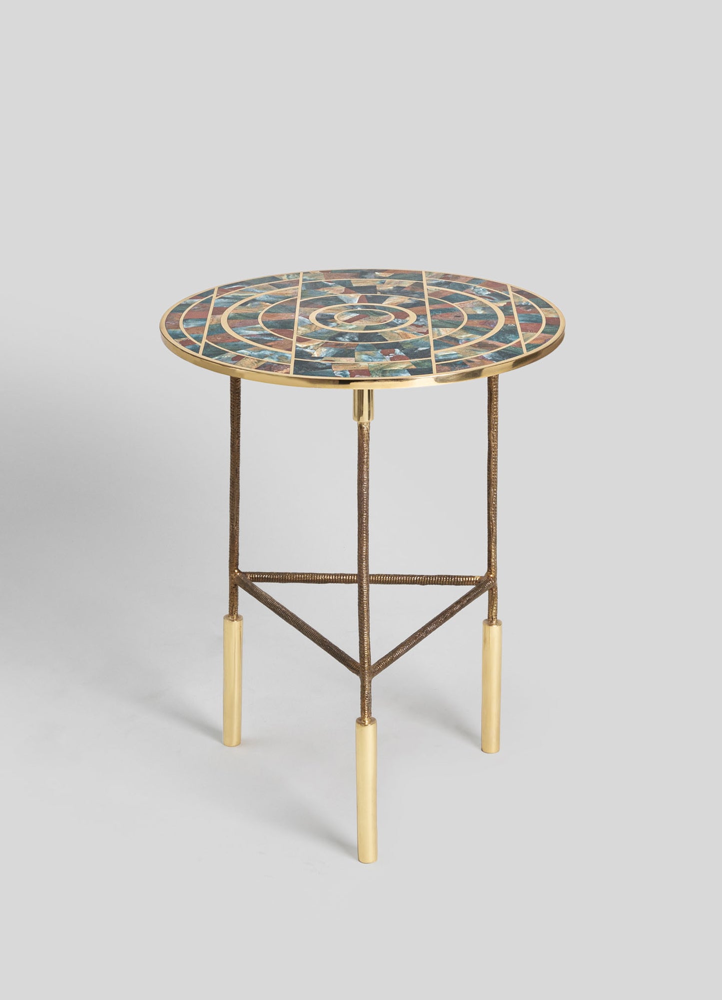 Round side table with a mosaic top featuring multicolored stone tiles and a gilt metal rim. The table has slender, textured metal legs with gold-tone tips, combining contemporary design with artistic craftsmanship.
