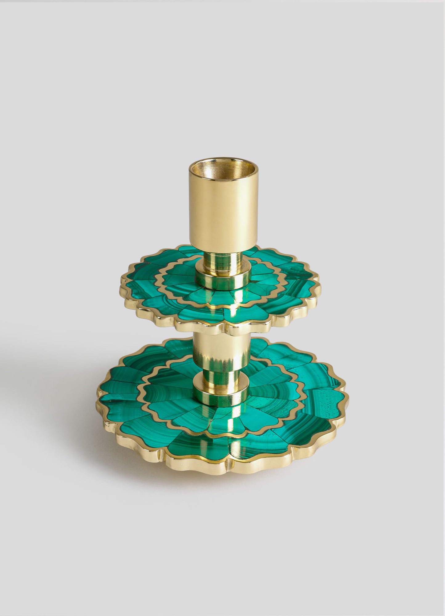 A three-tiered candle holder made of metal and malachite-like inlay with a gold finish, featuring scalloped edges and a cylindrical candle socket on the top tier.